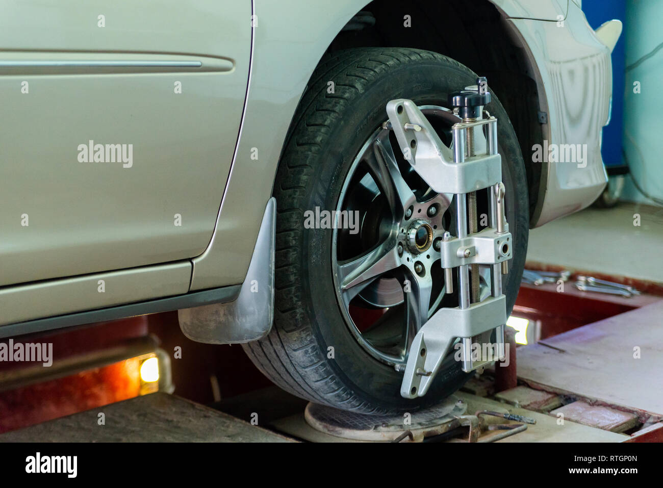 Auto su piedistallo con sensori sulle ruote per allineamento delle ruote controllo campanatura in officina della stazione di servizio. Foto Stock