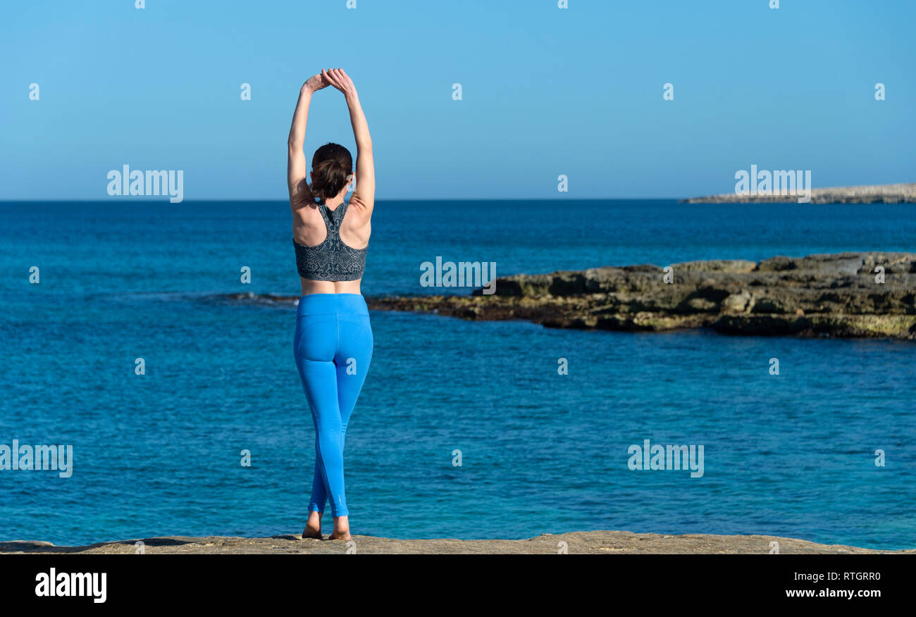 Vista posteriore di una donna facendo un tratto del braccio sopra la sua testa dal mare mediterraneo Foto Stock