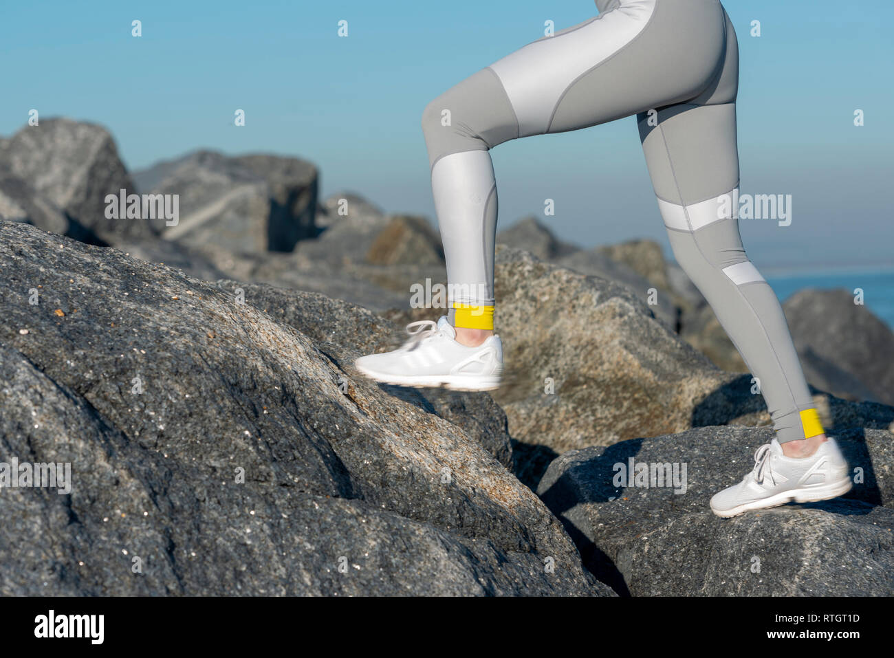 In prossimità di una donna corridori gambe in gambali in esecuzione attraverso le rocce Foto Stock