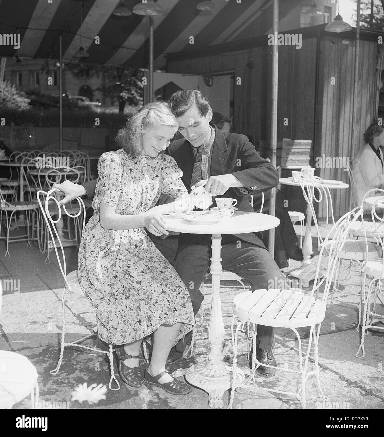 1940s stile di vita una tipica fika. Una giovane coppia in una caffetteria all'aperto. Versa il suo caffè. Sono attori Birger Malmsten, 1920-1991 e Doris Svedlund, 1926-1985. Svezia. Foto Kristoffersson Ref U62-6. Svezia 1946 Foto Stock