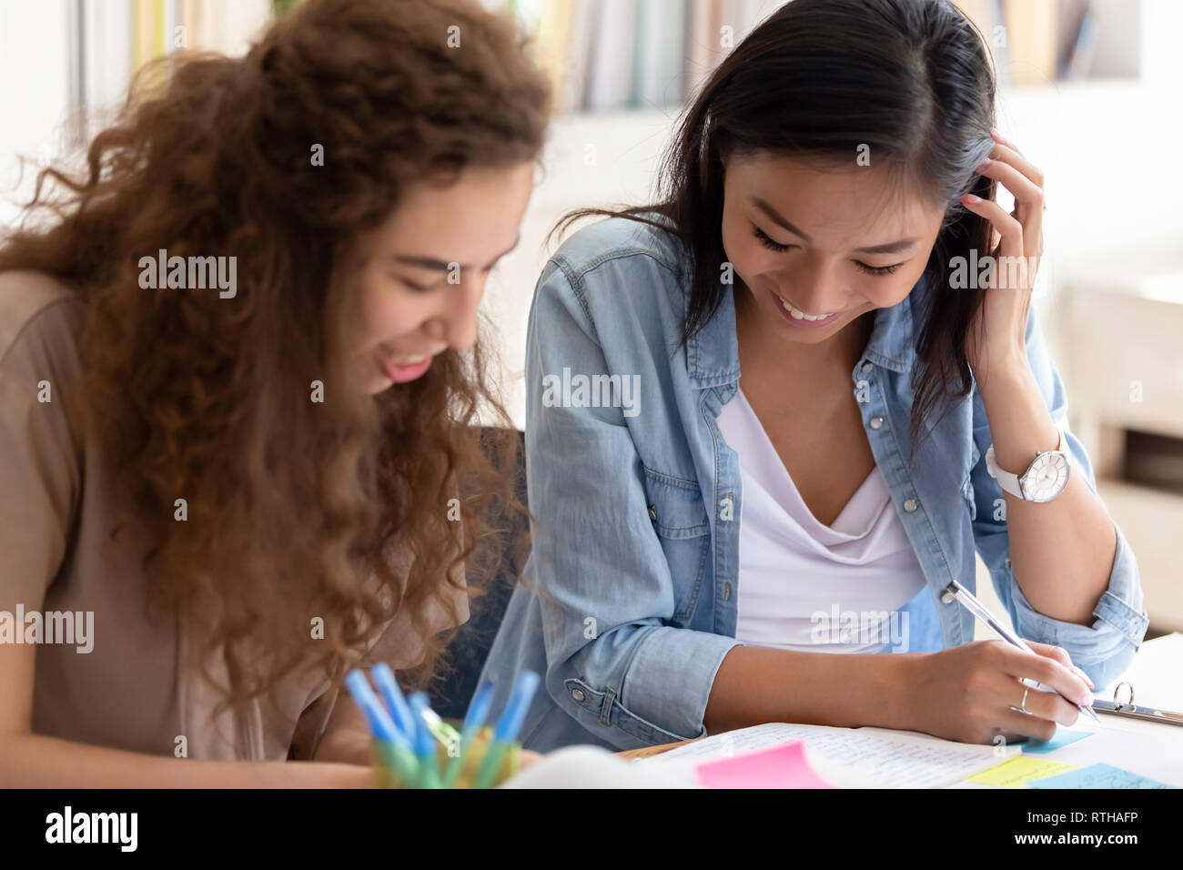Due lieti diverse ragazze college amici che studiano insieme nel campus Foto Stock