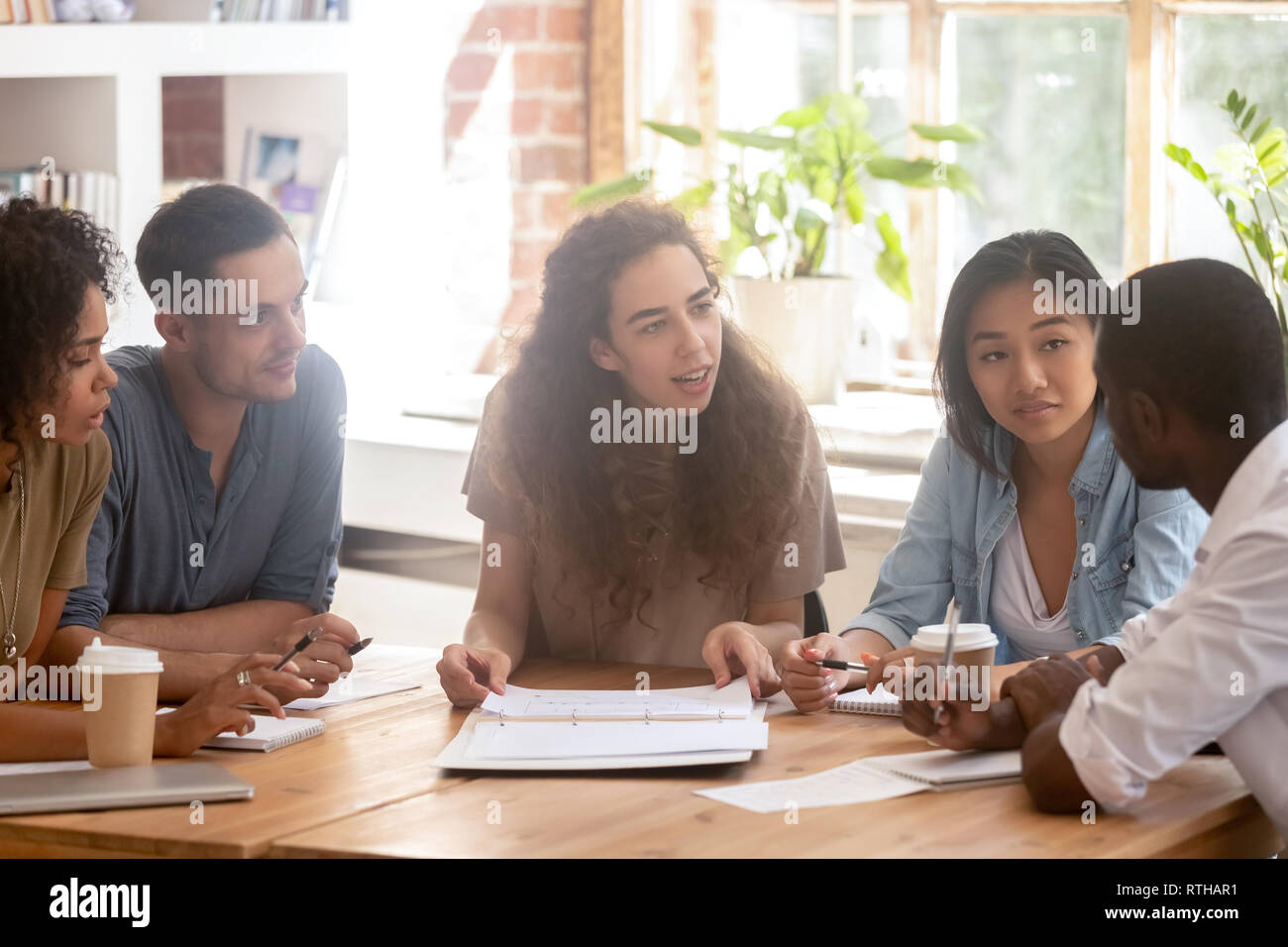 Diversi colleghi in ascolto al collega africano raccontando idea alla riunione Foto Stock