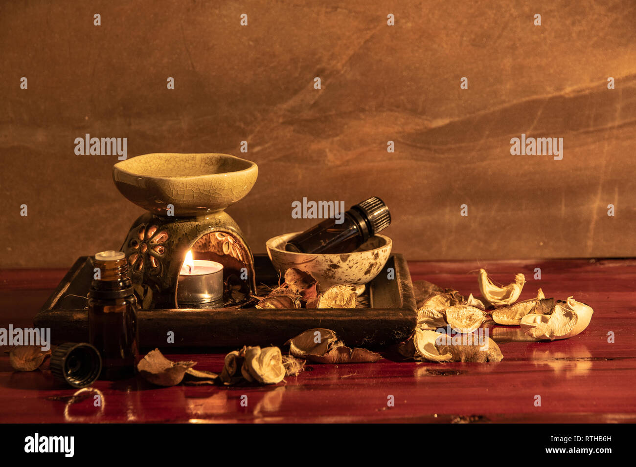 Lampada di aroma con olio essenziale e pot-pourri sul tavolo di legno dello sfondo. Foto Stock