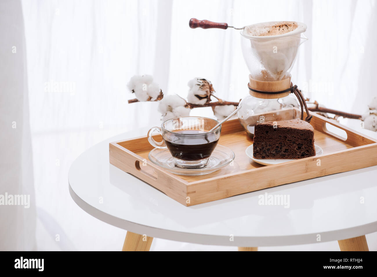 Caffè di gocciolamento sul vassoio in legno con torta al cioccolato. Tempo di caffè sul cafe con luce naturale Foto Stock