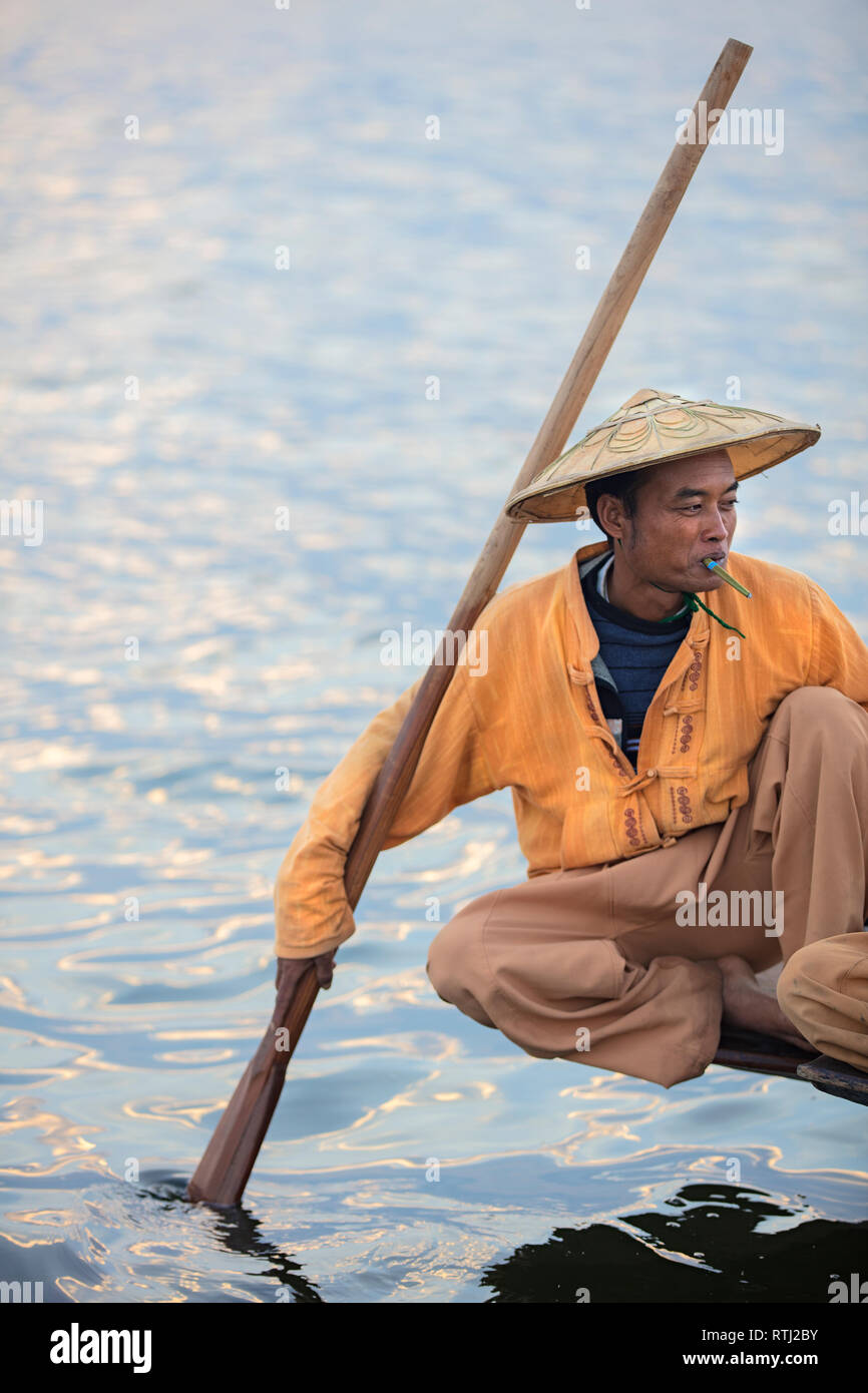 Ritratto di un pescatore birmano che fuma tabacco su una barca di legno nel lago Inle, Myanmar. Foto Stock