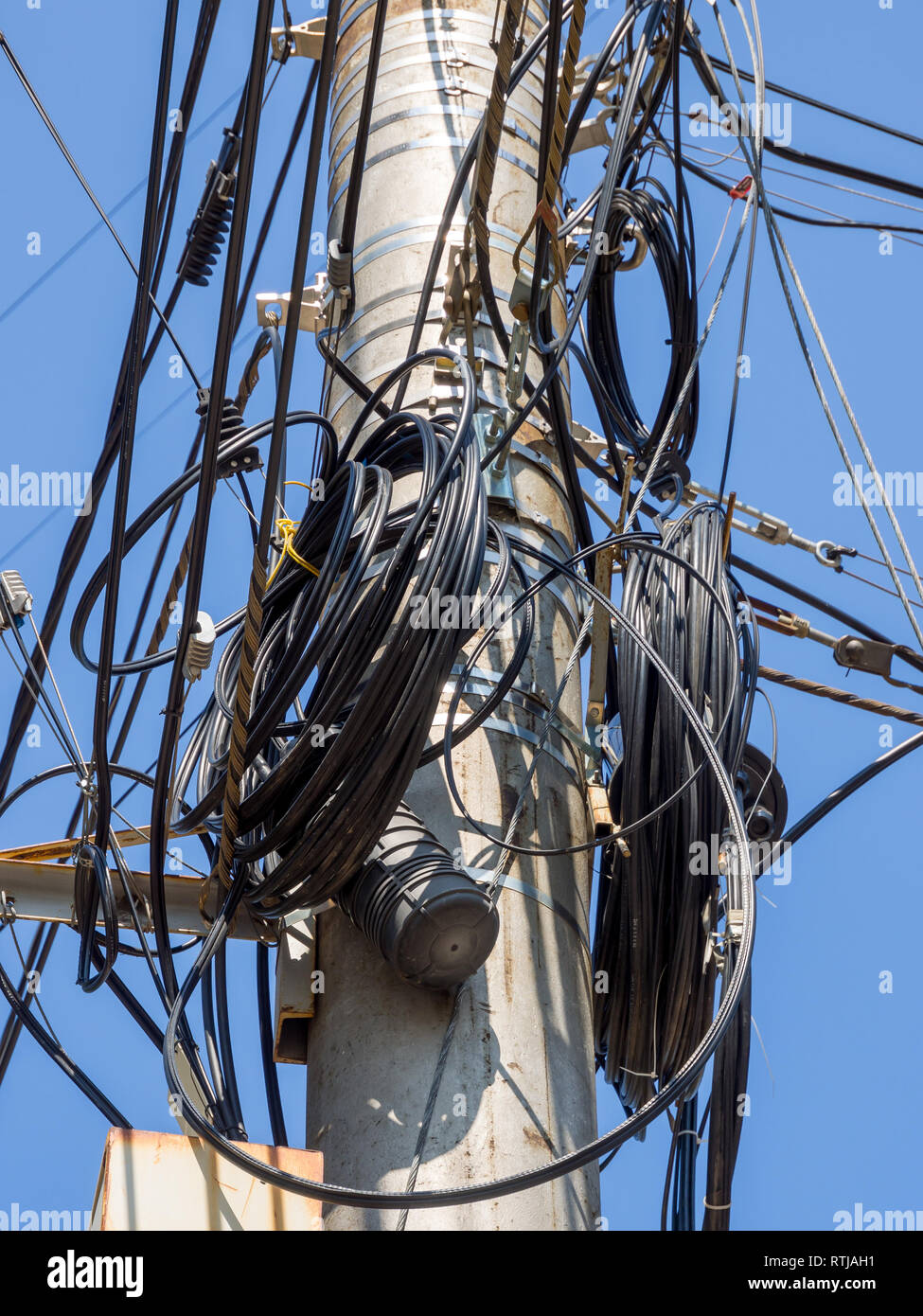 Polo di calcestruzzo con le spire della riserva di un cavo telefonico Foto Stock