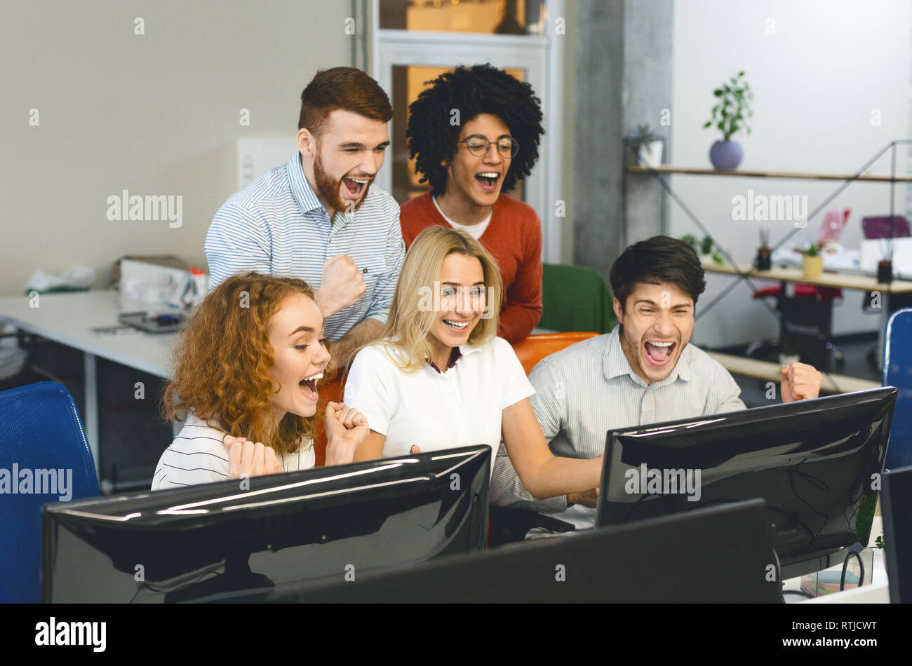 Il team di Business guardando lo schermo del computer celebrando la vittoria Foto Stock