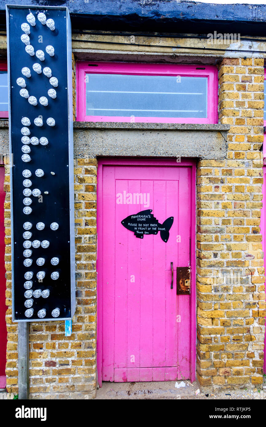 Margate porto. Porta Rosa nel muro di mattoni con finestra al di sopra di esso. Grande caffè segno accanto alla porta. A forma di pesce avviso imbastito per porta. Foto Stock