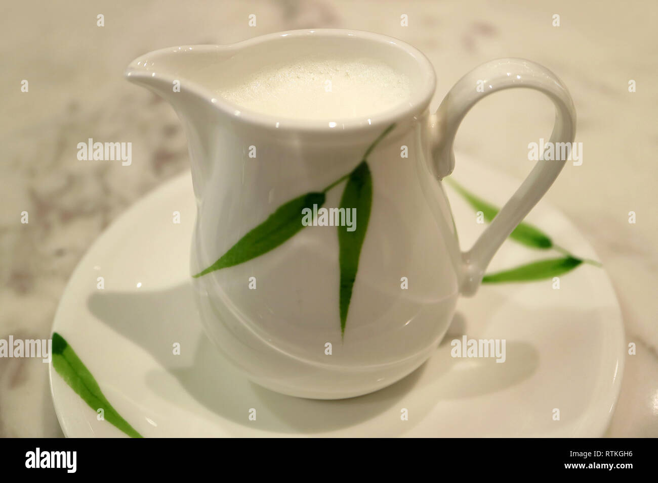 Bianco con foglia verde modello brocca del latte su un piattino Foto Stock