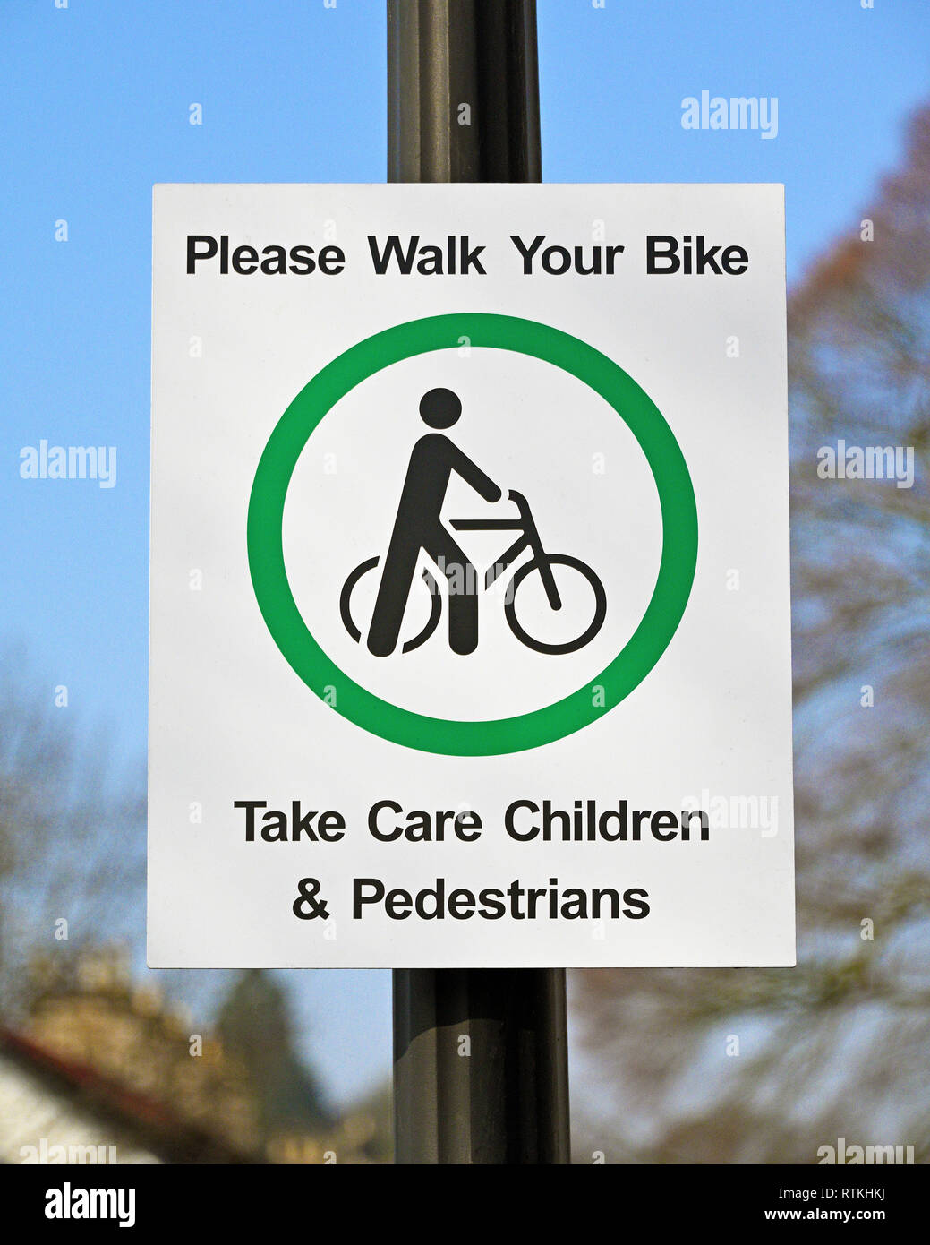 Il simbolo di sicurezza. "Si prega di camminare la tua moto. Prendersi cura dei bambini & Pedoni". K Village, Kendal Cumbria, England, Regno Unito, Europa. Foto Stock