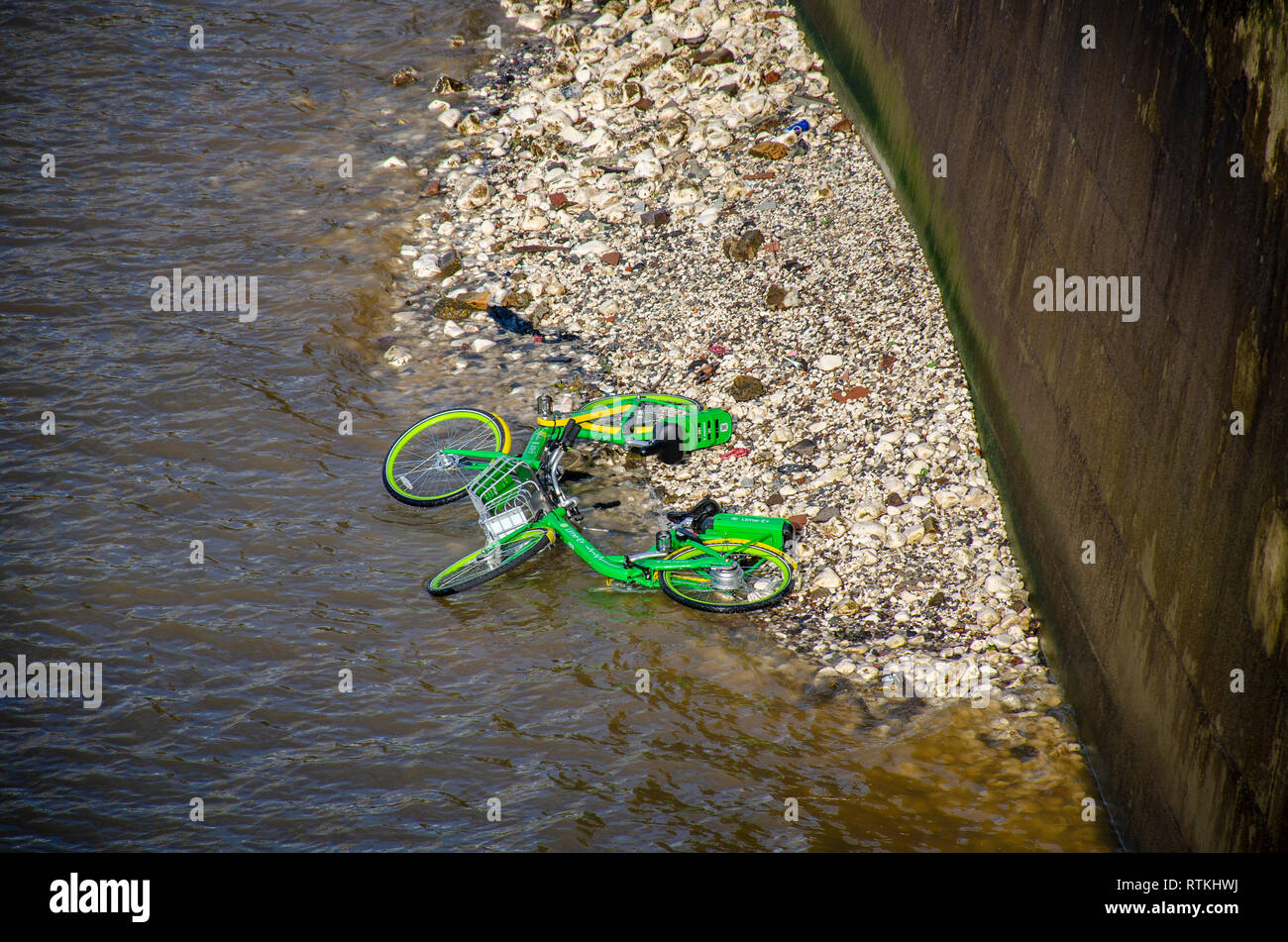 Londra, UK, 13 Febbraio 2019 Due Lime dockless biciclette elettriche ebikes oggetto di pratiche di dumping nel Tamigi vicino al London Eye. Foto Stock