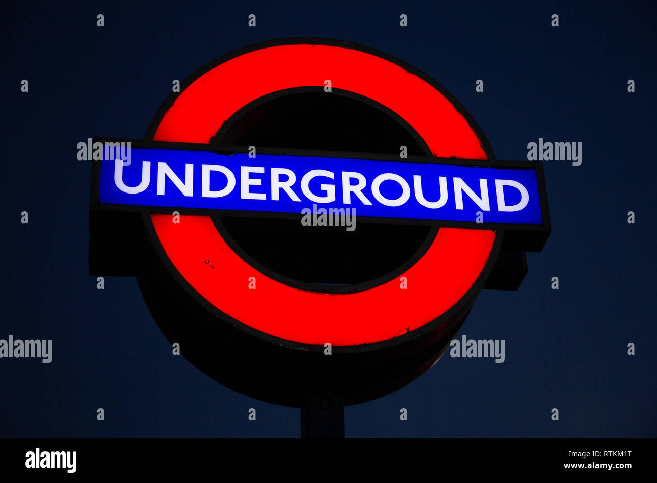 La metropolitana di Londra segno di notte, contro il cielo chiaro. Foto Stock