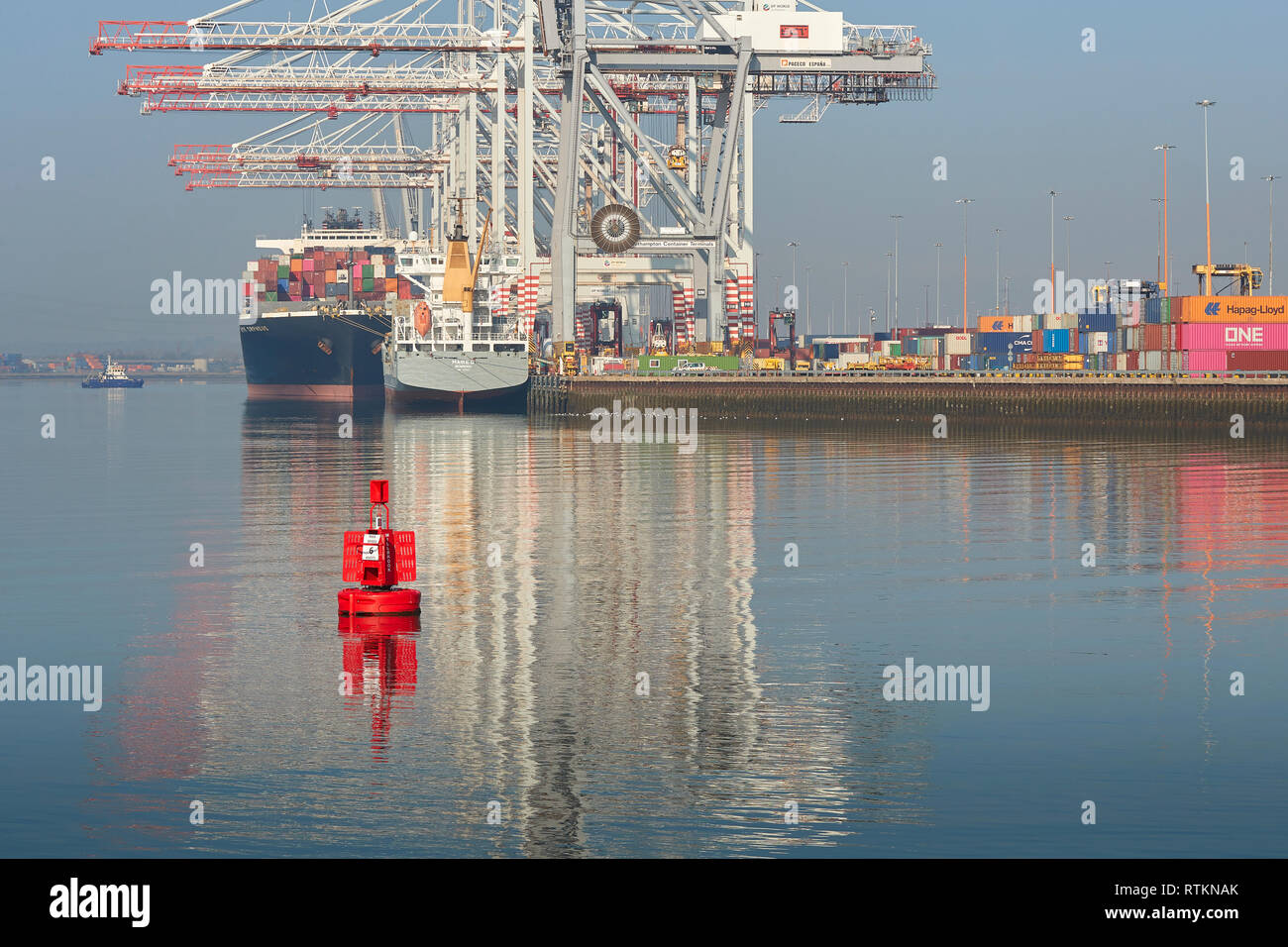 Riflessioni in acqua come il piccolo contenitore Nave, MAIKE D, anteriore e il contenitore più grande nave, NRK ORFEO, dietro, vengono caricate e scaricate. Regno Unito. Foto Stock