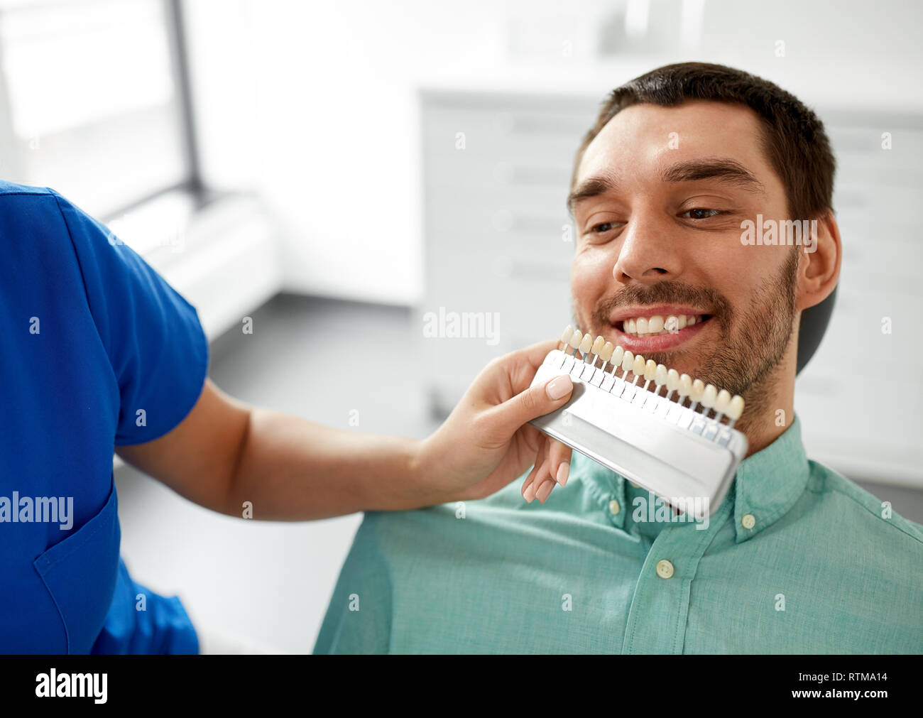 Dentista scegliendo il colore del dente per il paziente presso la clinica Foto Stock