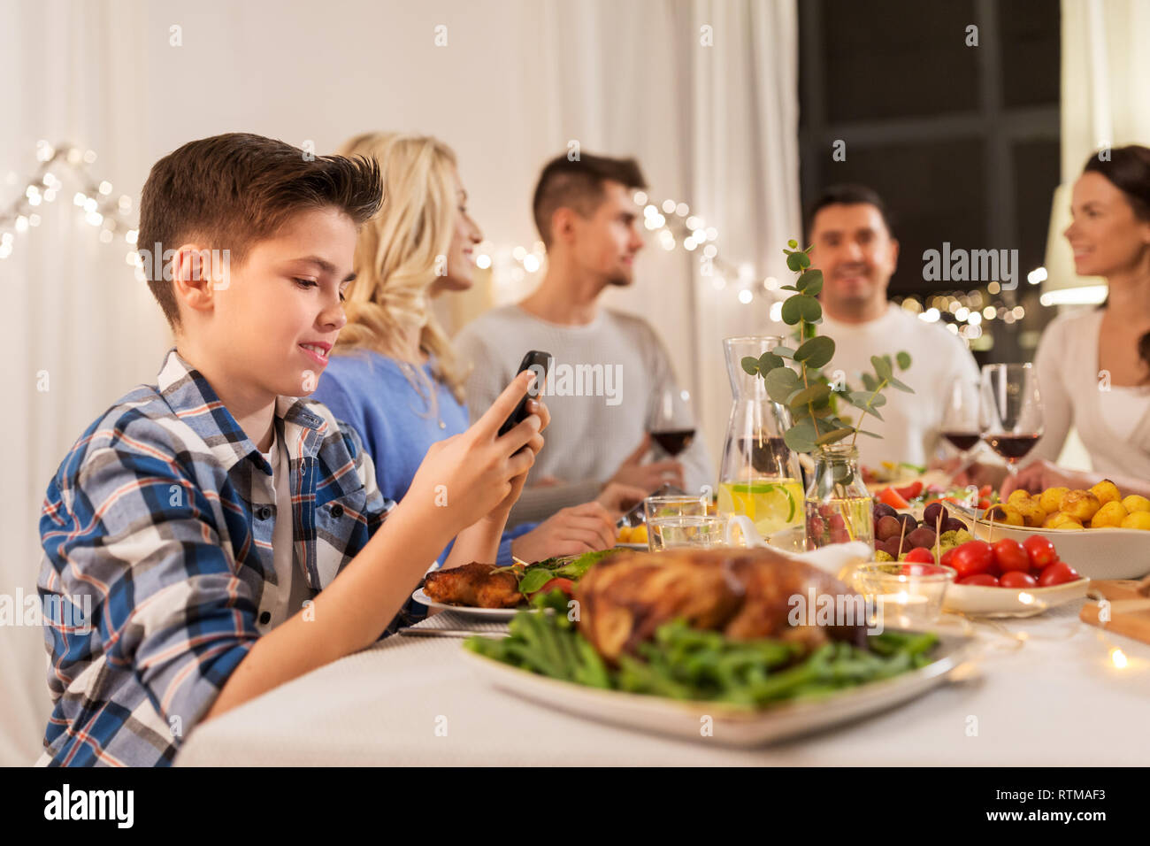 Ragazzo con smartphone a cena in famiglia party Foto Stock
