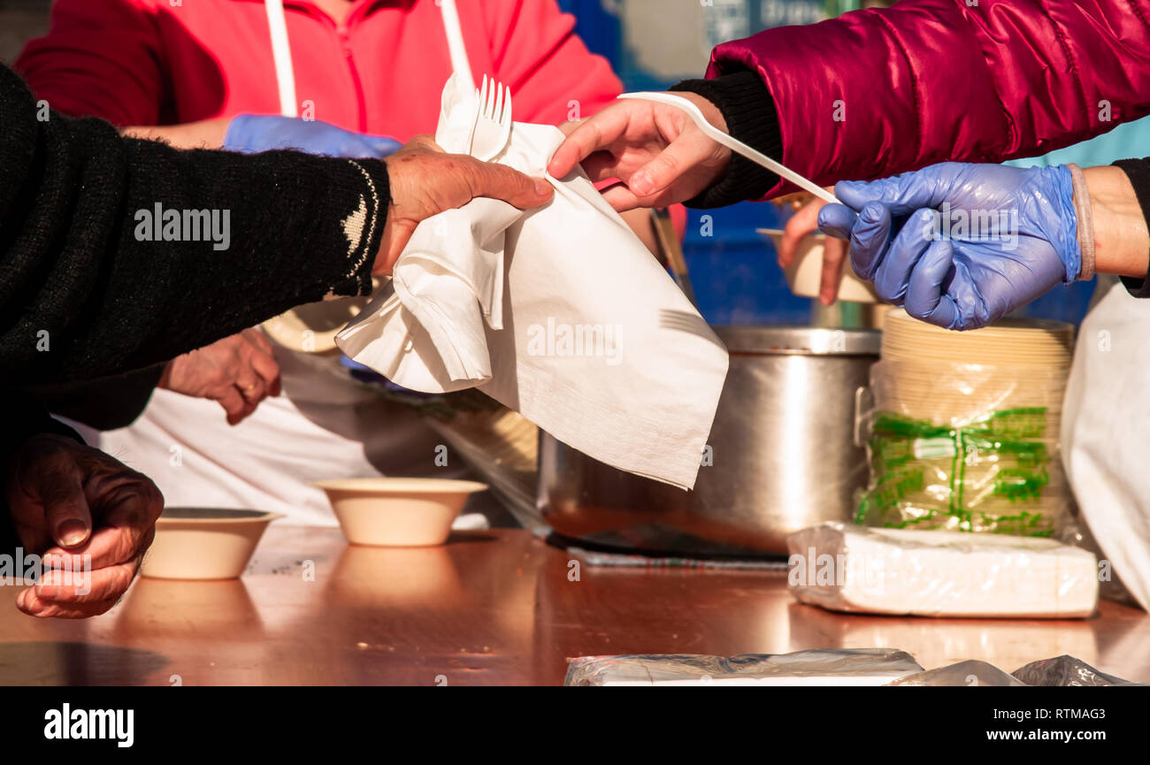 Una persona che indossa guanti in nitrile blu immissione di tovaglioli di carta, plastica forcelle e piastre di carta su un tavolo durante una festa di strada Foto Stock