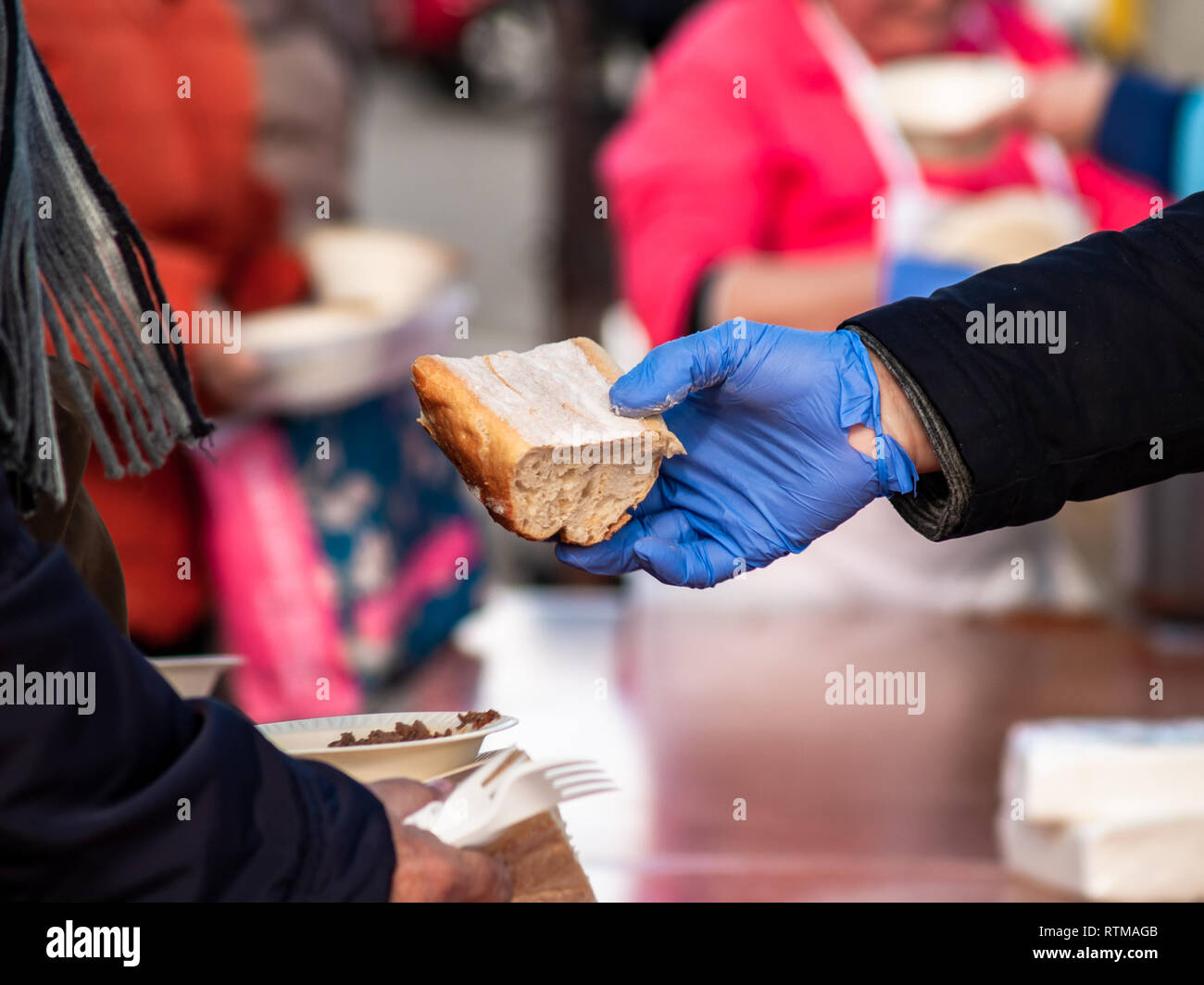 Una persona con guanti in nitrile blu che serve un pezzo di pane Foto Stock