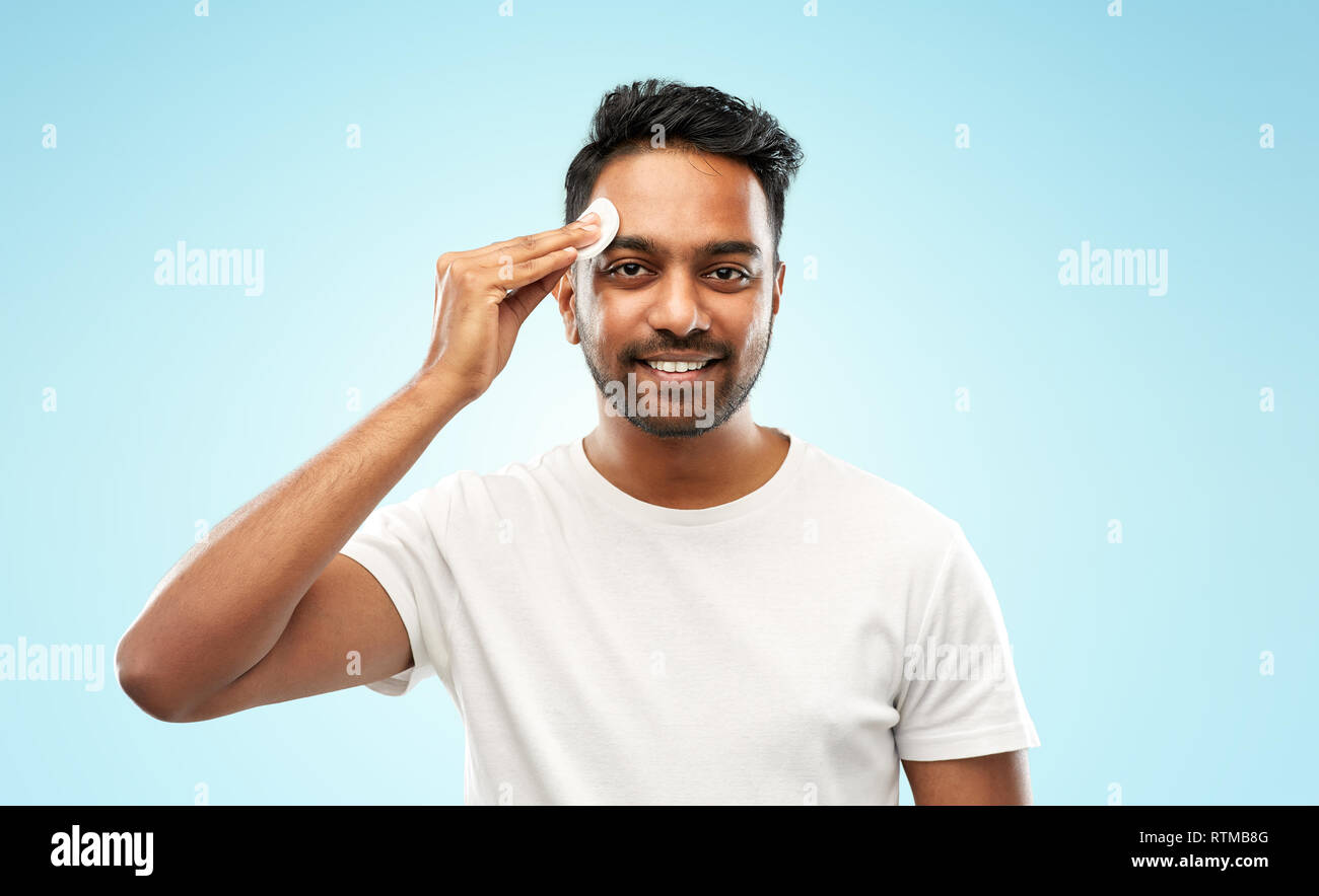 Sorridente uomo indiano la pulizia viso con tampone di cotone Foto Stock