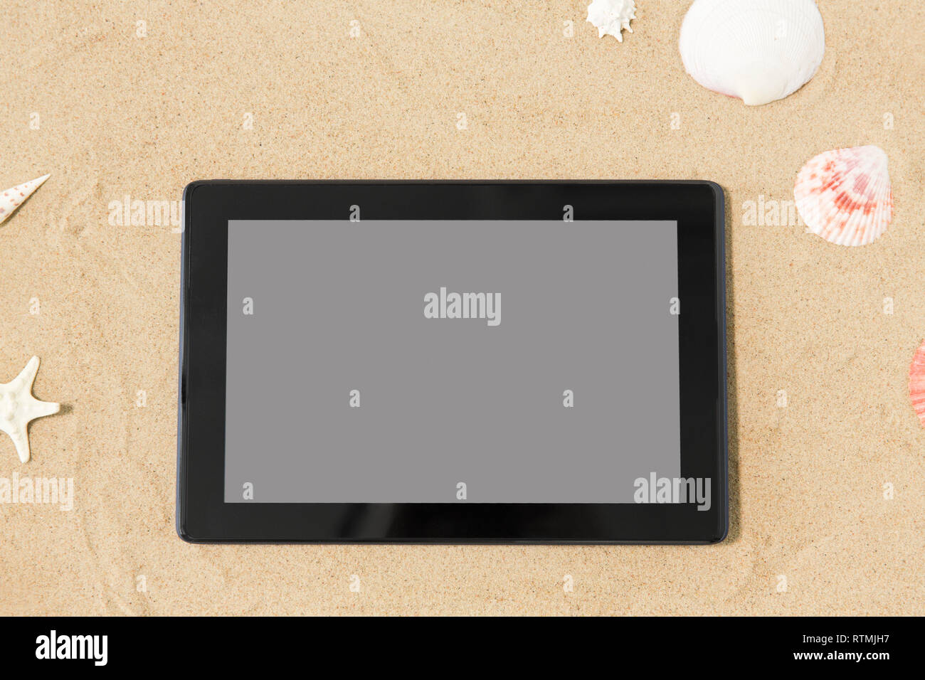 Tablet PC e conchiglie sulla spiaggia di sabbia Foto Stock