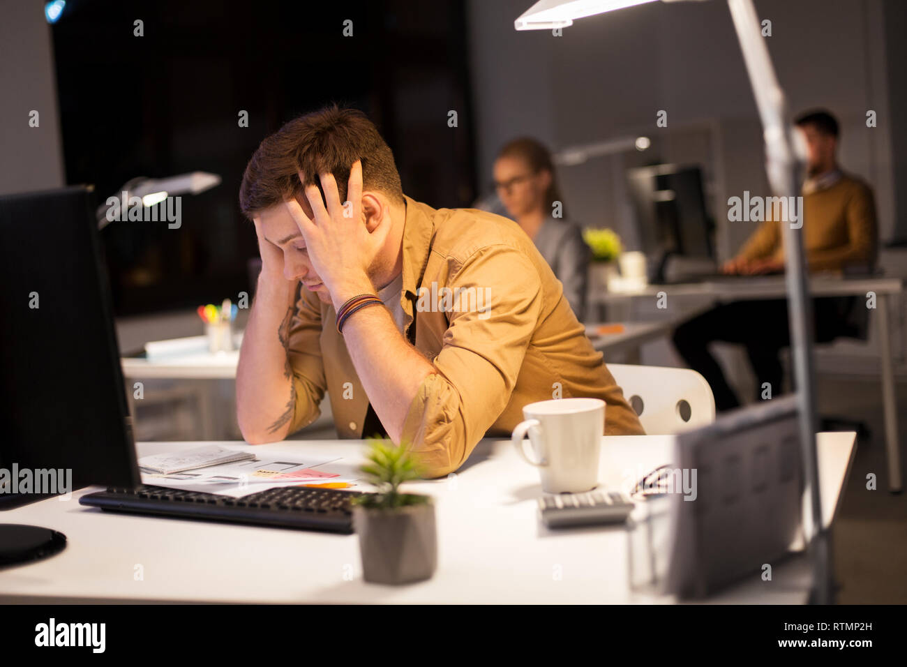 Ha sottolineato l'uomo al monitor del computer in ufficio di notte Foto Stock