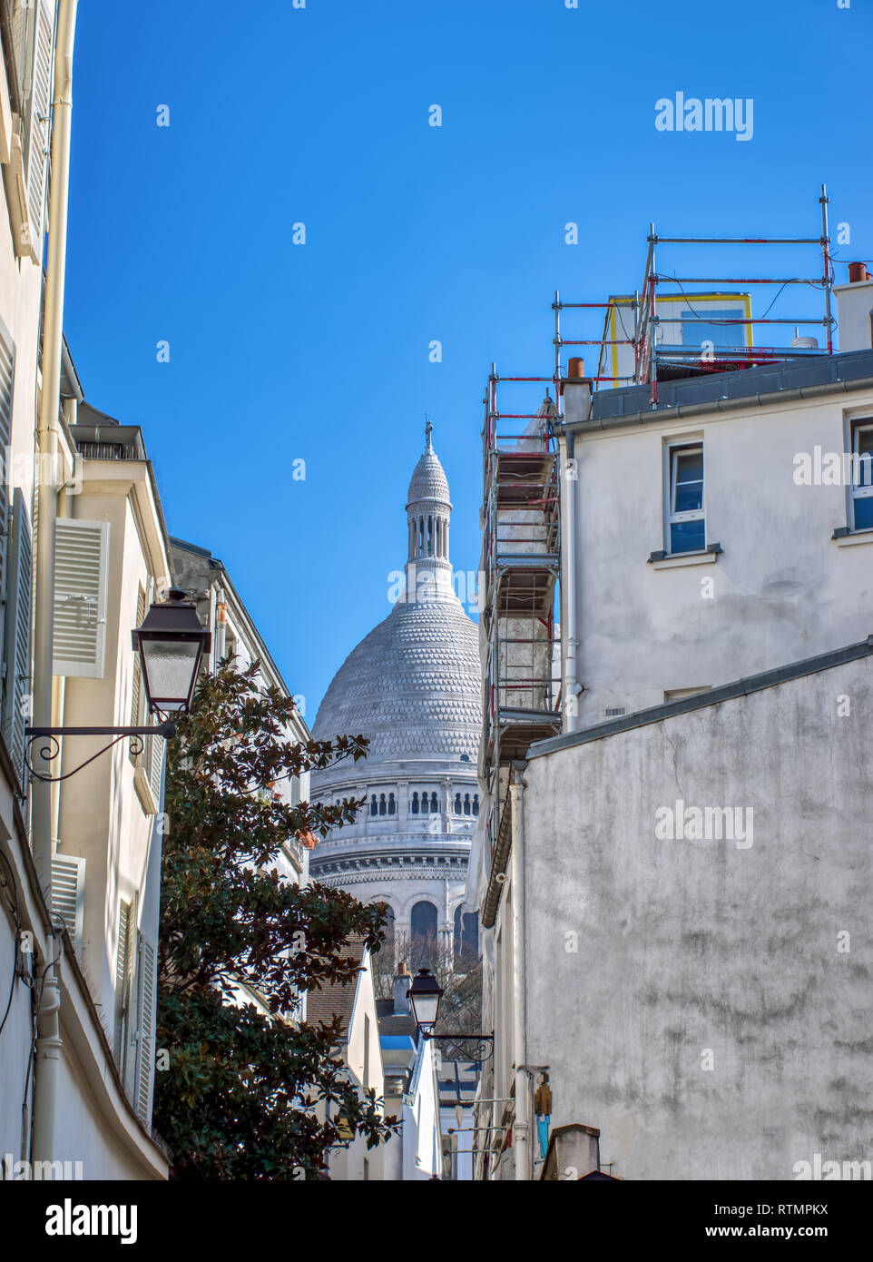 Il Sacre Coeur da una stretta strada del quartiere di Montmartre a Parigi Foto Stock