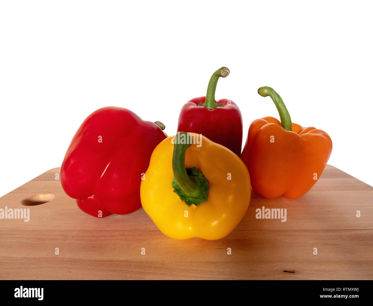 Quattro colorati in modo diverso i peperoni su una tavola di legno di fronte a uno sfondo bianco Foto Stock