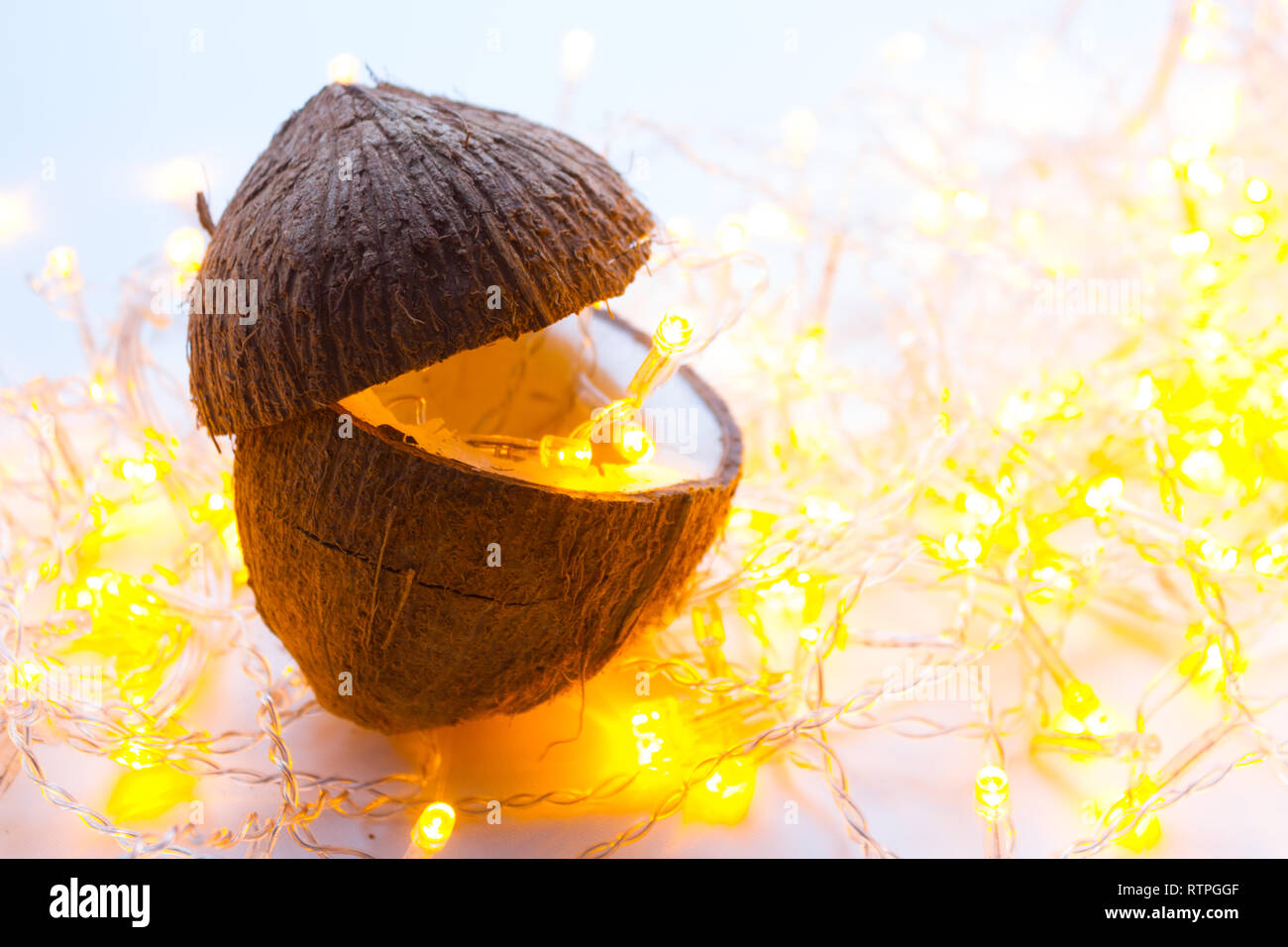 Una noce di cocco sul tavolo. ghirlanda con luce gialla Foto Stock