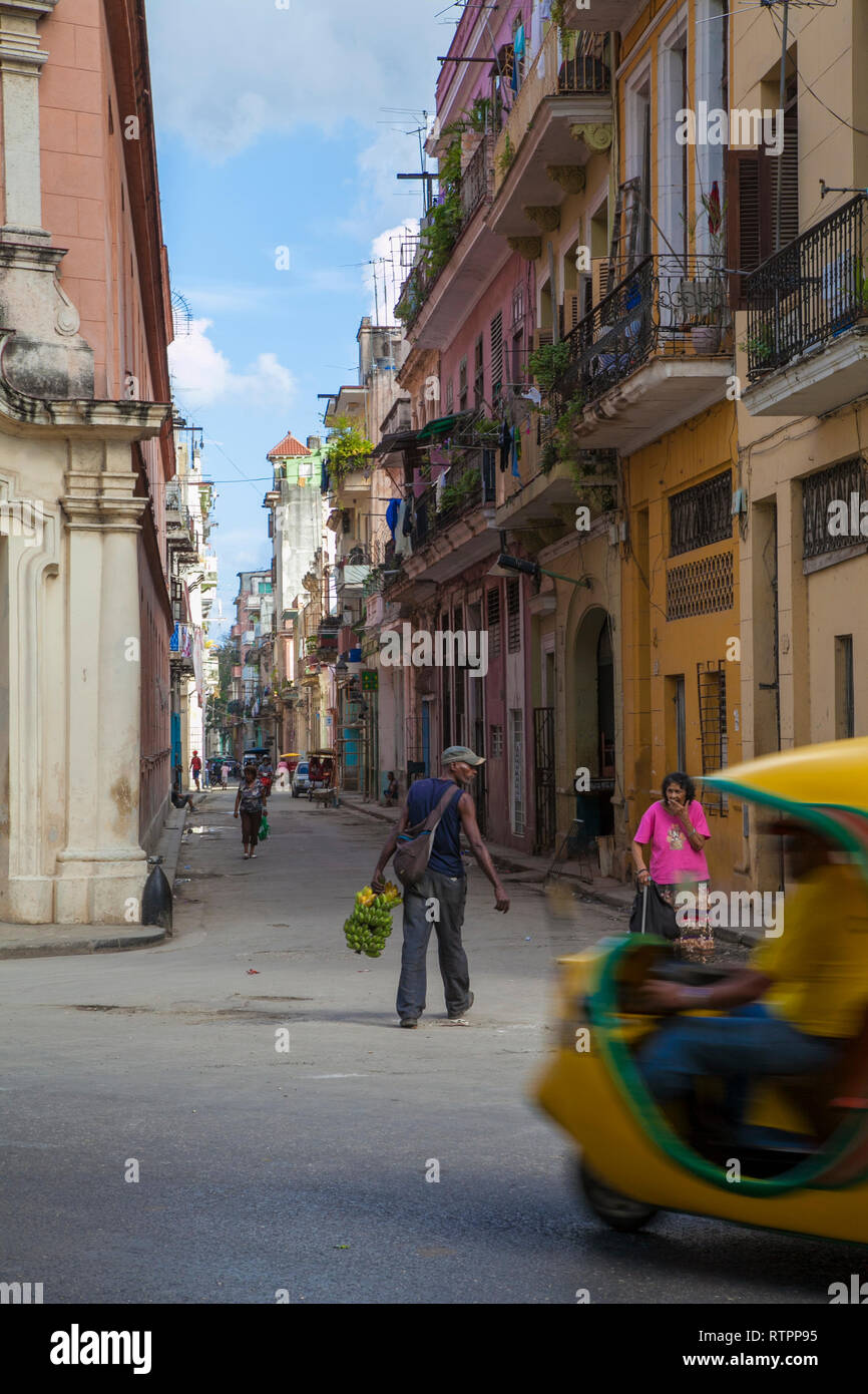 L'Avana, Cuba - 06 Gennaio 2013: una vista delle strade della città con il popolo cubano. Un uomo cammina in mezzo alla strada, un taxi in primo piano Foto Stock