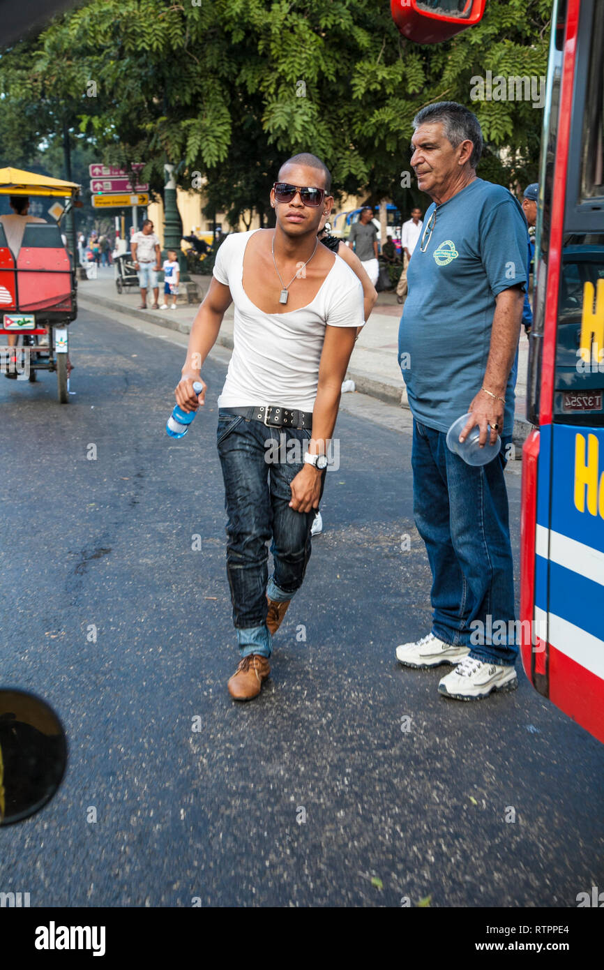 L'Avana, Cuba - 12 Gennaio 2013: una vista delle strade della città con il popolo cubano. Un giovane uomo affretta il bus all'ingresso. Foto Stock