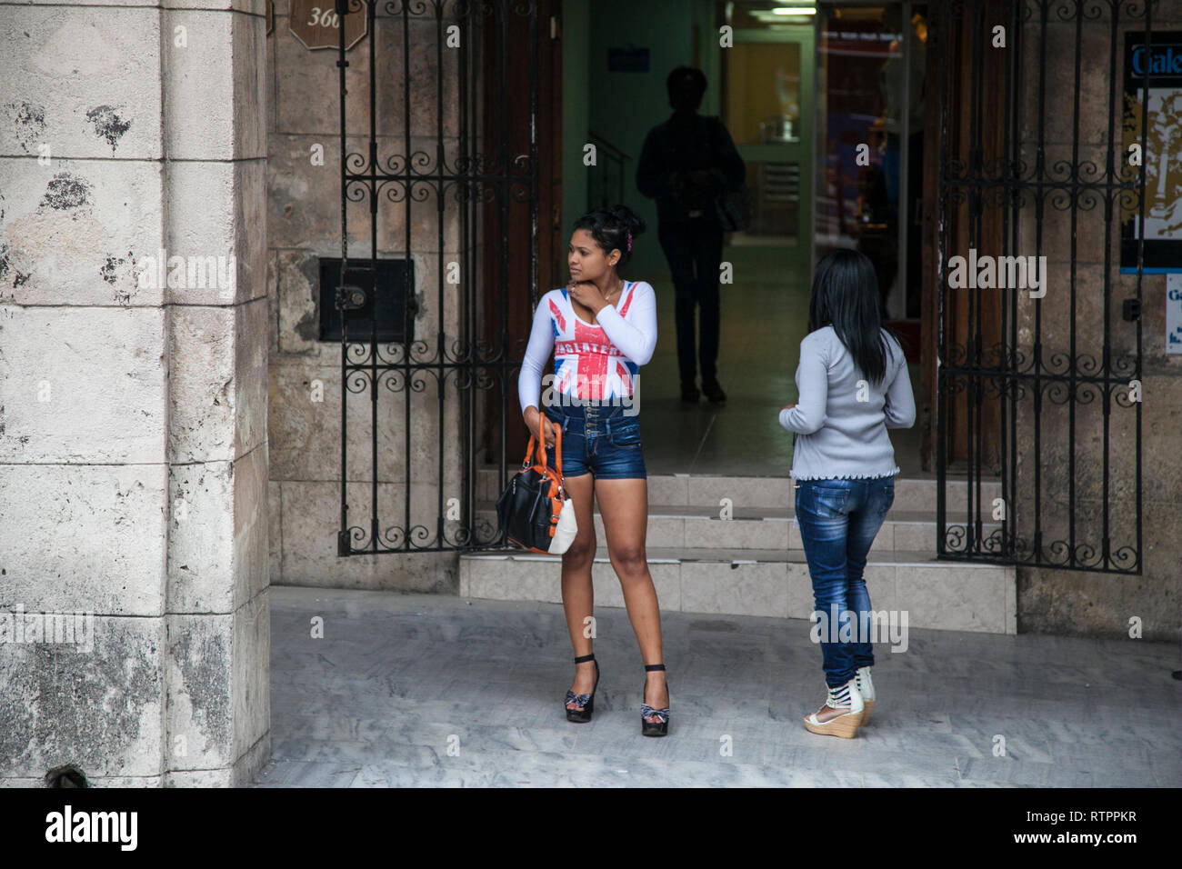 L'Avana, Cuba - 19 Gennaio 2013: una vista delle strade della città con il popolo cubano. Due giovani donne in attesa in strada. Foto Stock