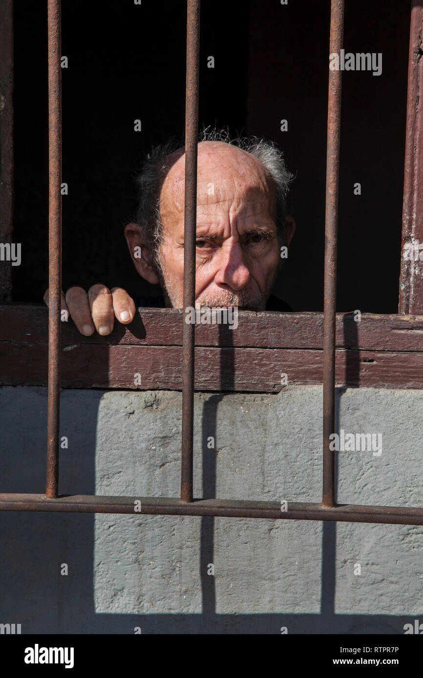 L'Avana, Cuba - 21 Gennaio 2013: una vista delle strade della città con il popolo cubano. Un uomo anziano guarda fuori la porta all'esterno. Foto Stock