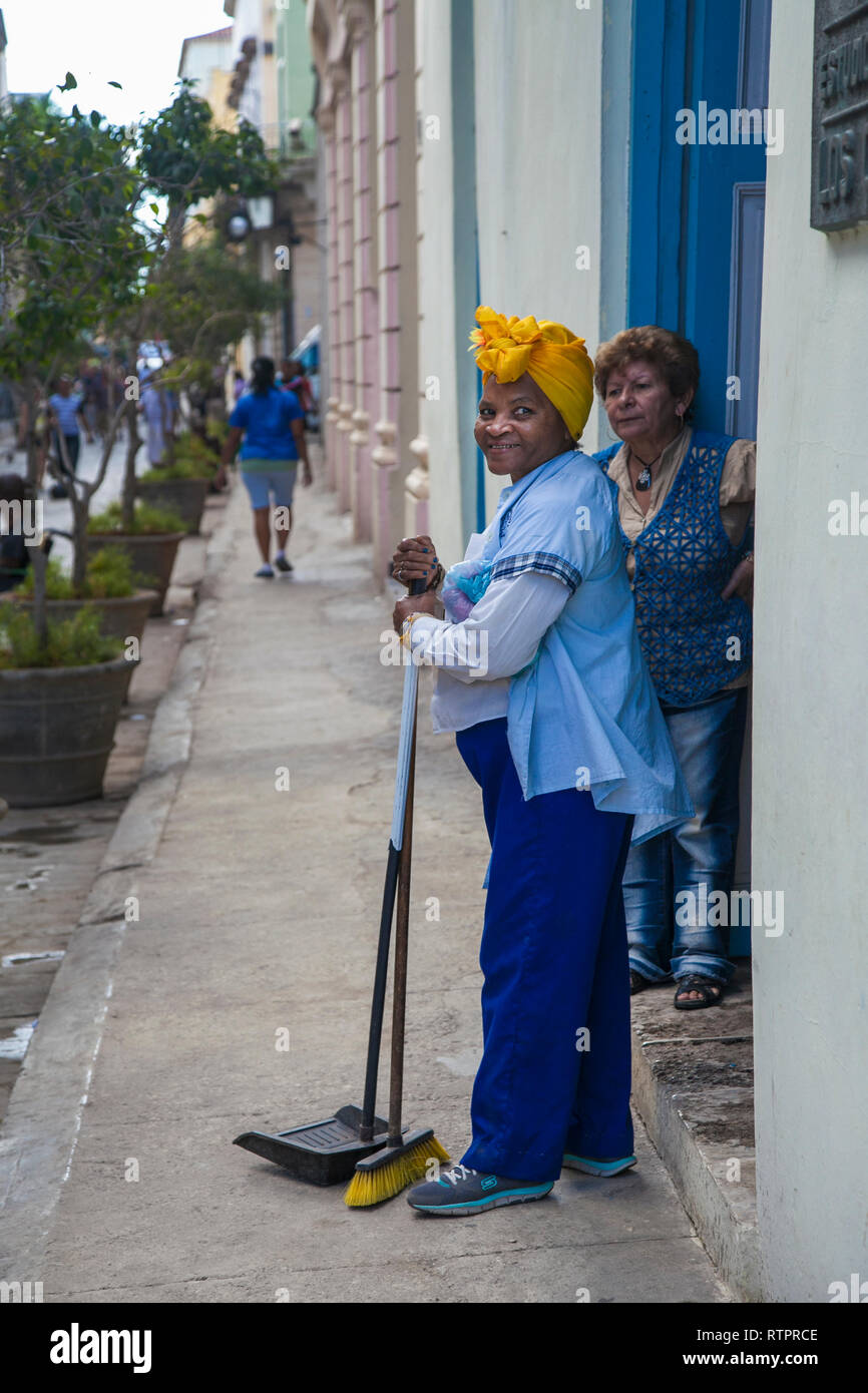 L'Avana, Cuba - 22 Gennaio 2013: una vista delle strade della città con il popolo cubano. Una donna delle pulizie colloqui per i residenti della casa. Foto Stock