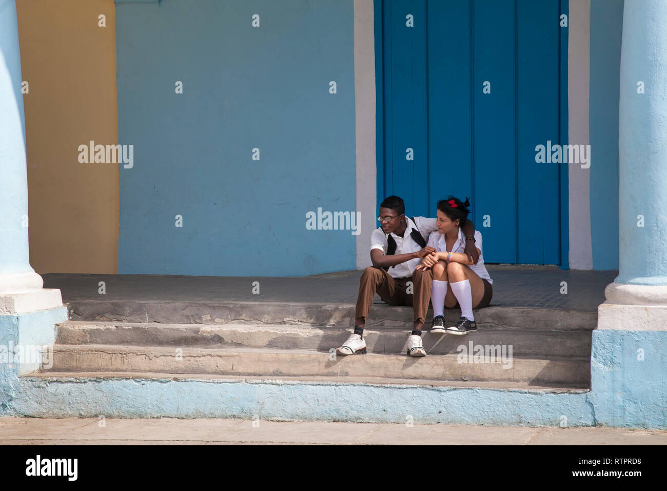 L'Avana, Cuba - 22 Gennaio 2013: una vista delle strade della città con il popolo cubano. Una giovane coppia abbracci seduta sulle scale. Foto Stock