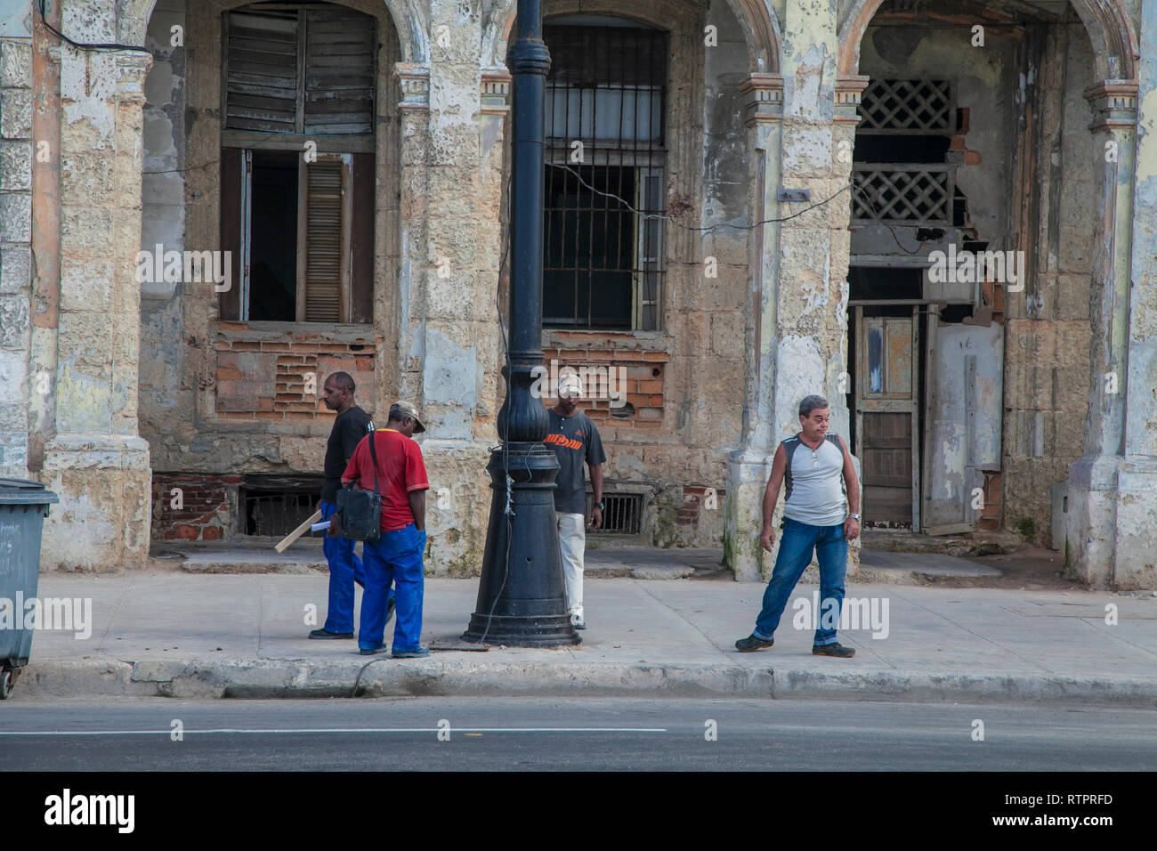 L'Avana, Cuba - 22 Gennaio 2013: una vista delle strade della città con il popolo cubano. Quattro uomini sono in attesa per il bus. Foto Stock