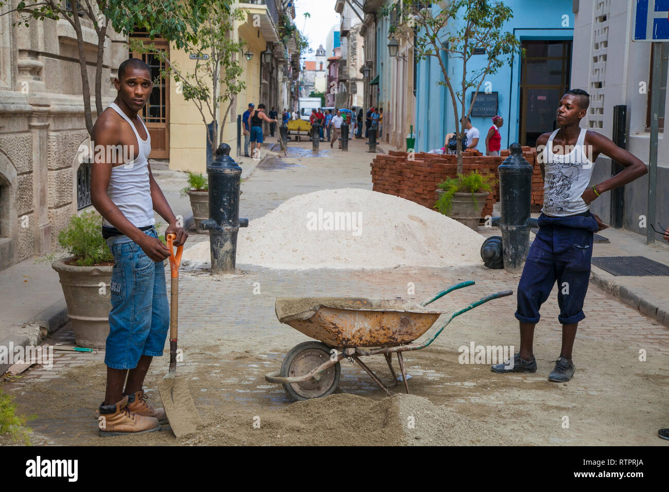 L'Avana, Cuba - 24 Gennaio 2013: una vista delle strade della città con il popolo cubano. Due lavoratori edili pala sabbia in una carriola. Foto Stock