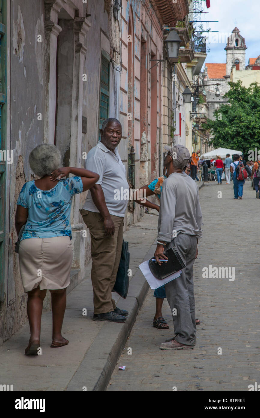 L'Avana, Cuba - 24 Gennaio 2013: una vista delle strade della città con il popolo cubano. Tre afro-cubano anziani parlare sulla strada. Foto Stock