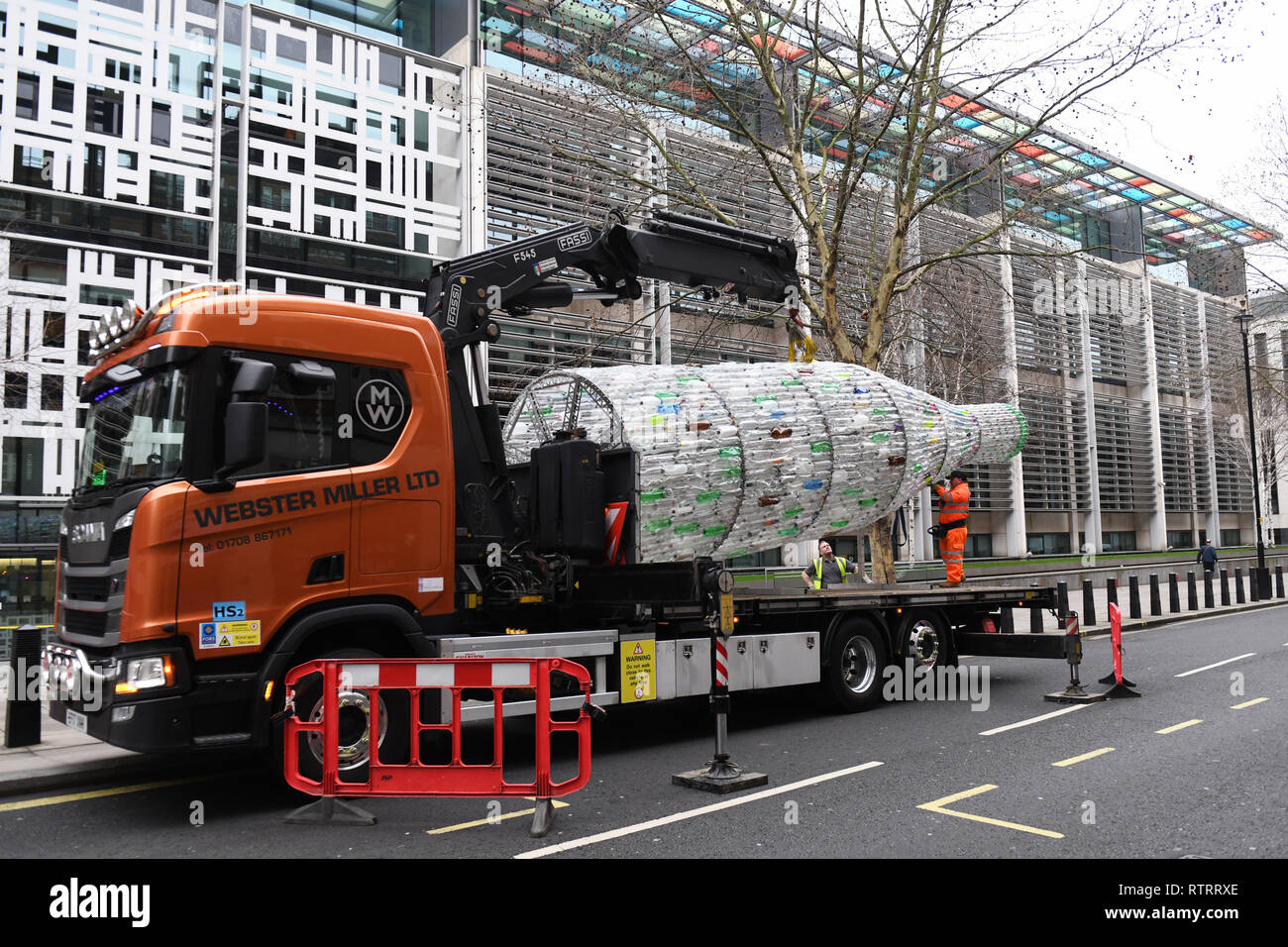 Un 29 piedi-lungo la bottiglia di plastica artwork da Lulu Quinn, fornito da attivisti di Greenpeace ad ambiente segretario Michael Gove lunedì presso il Dipartimento per l'ambiente, l'alimentazione e gli affari rurali all'Home Office di Londra, viene rimosso. Foto Stock