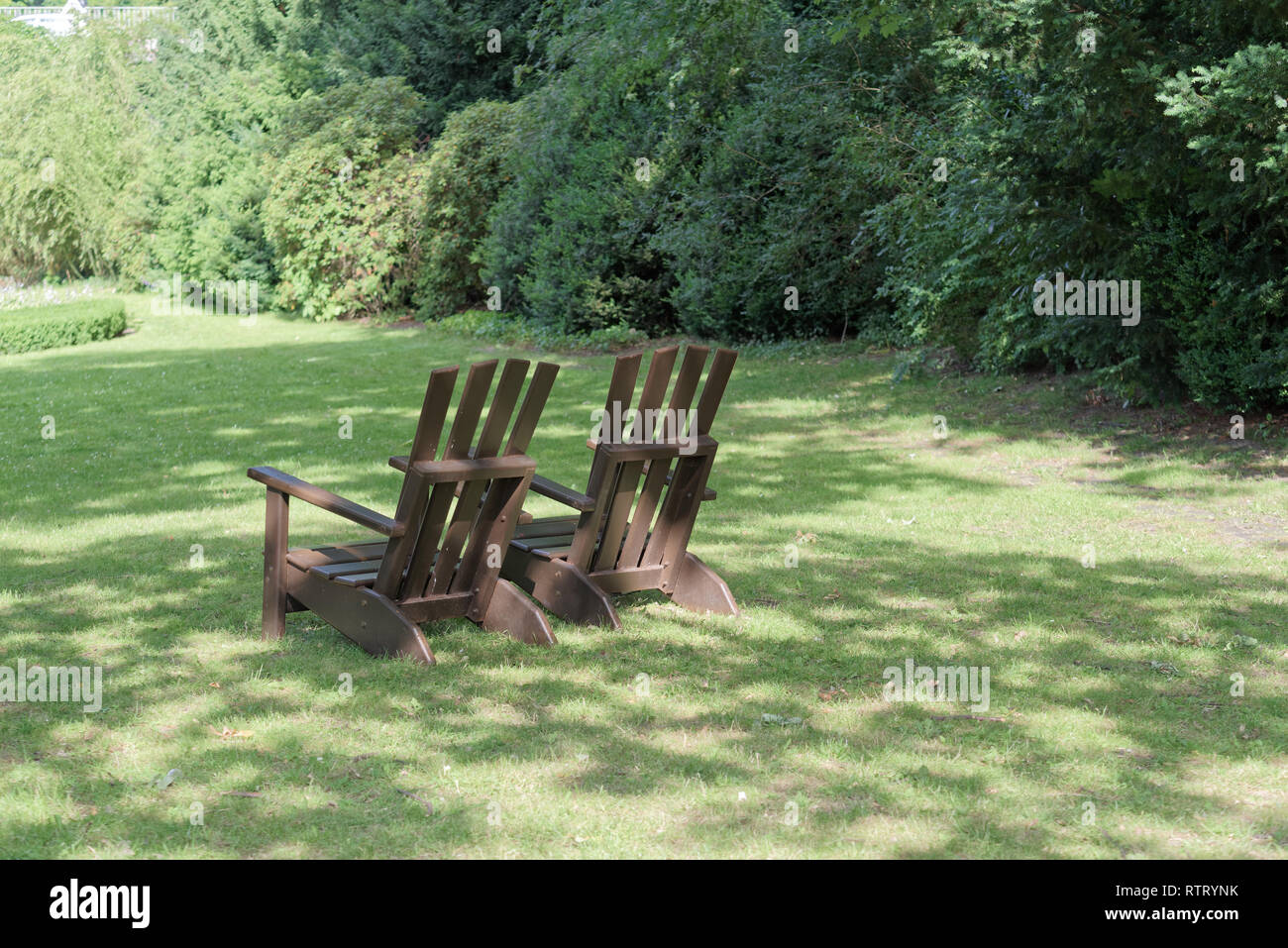 Due sedie di legno per rilassarsi sul prato verde in un parco pubblico. "Parco Planten un Blomen" giardino della città di Amburgo, Germania Foto Stock