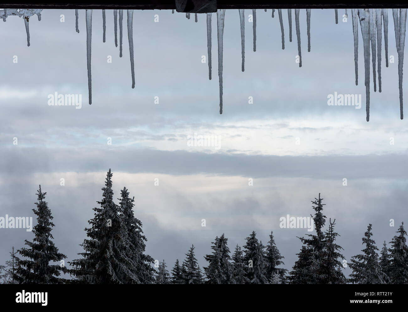 Inverno ghiaccioli su di un telaio di finestra con splendida vista di una foresta di montagna da una stazione sciistica Foto Stock