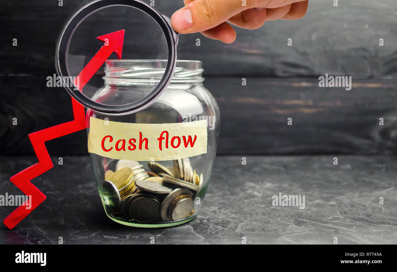 Vaso di vetro con monete e l'iscrizione ' flusso di cassa ' e la freccia verso l'alto. Piano finanziario. Gli investimenti e la crescita del patrimonio, piano di pensionamento, salari. Mone Foto Stock