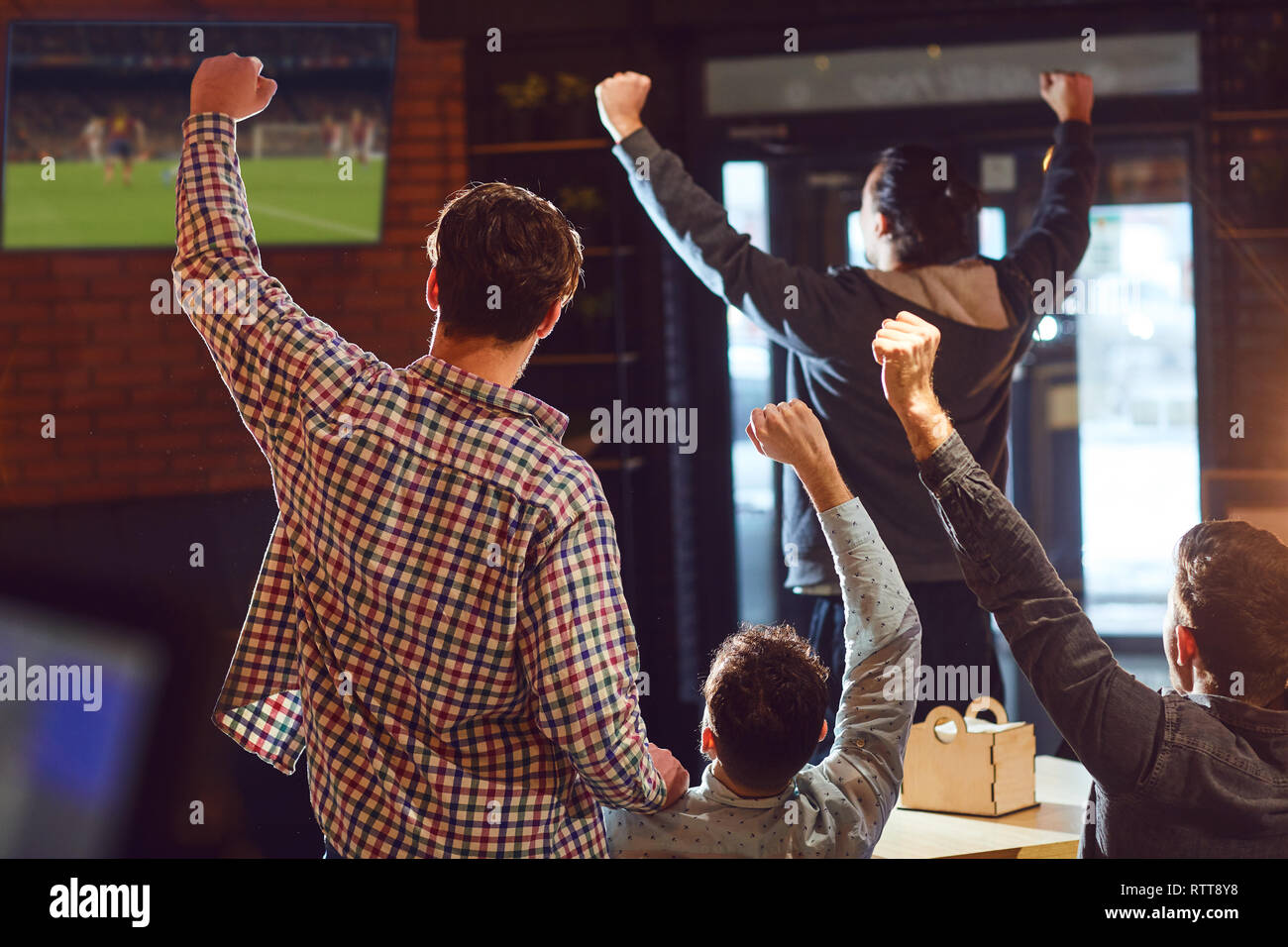 I giovani a guardare il calcio in TV nella barra. Foto Stock