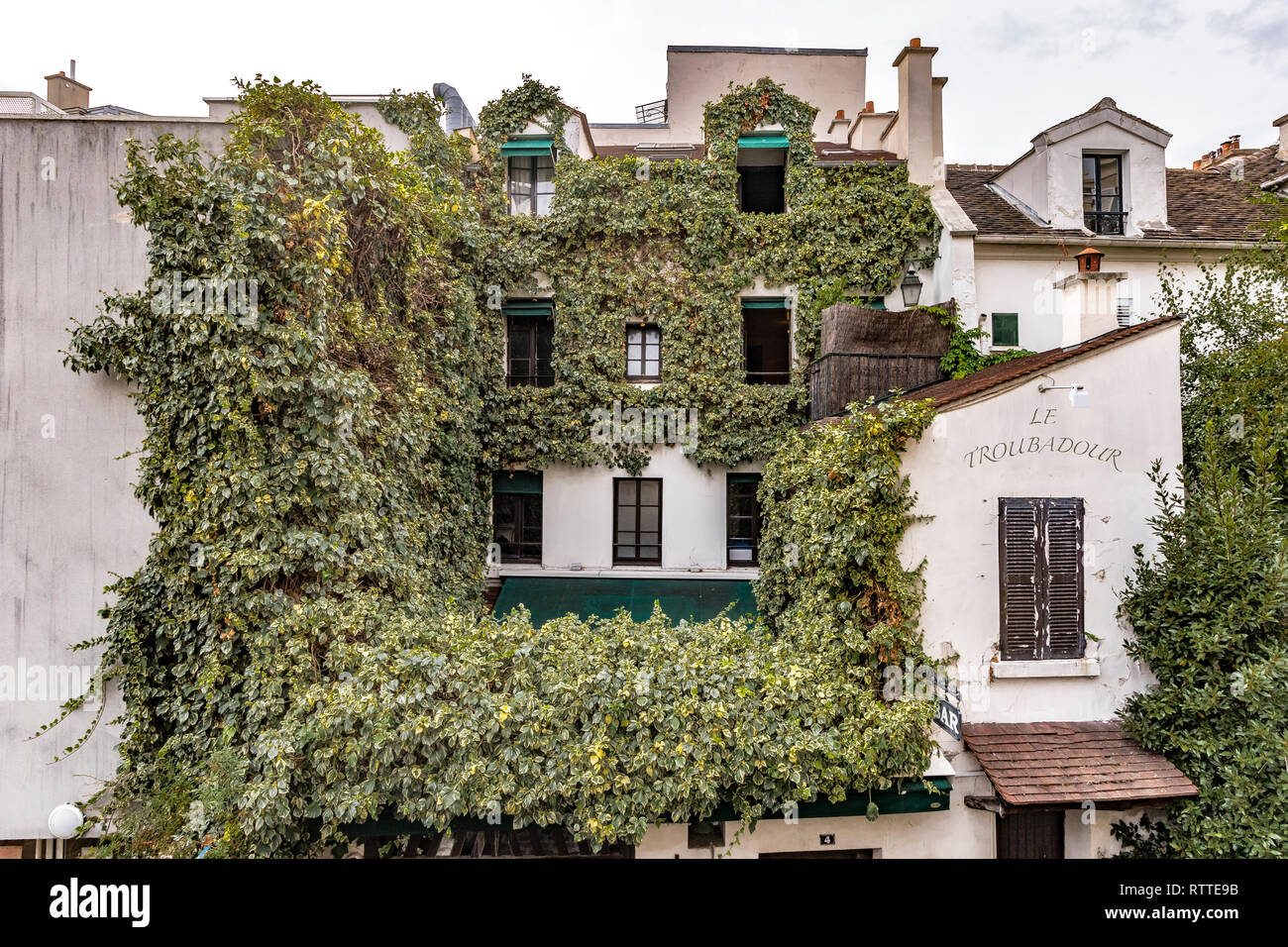 Ivy crescente sul muro di una casa di Montmartre che alloggia il Le Troubadour ristorante cafe, Parigi, Francia Foto Stock