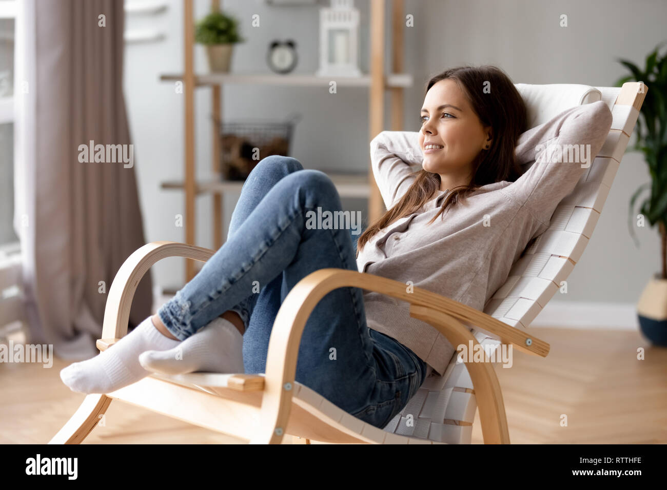 Sorridente ragazza rilassante Pendente ritornare in una sedia confortevole a casa Foto Stock