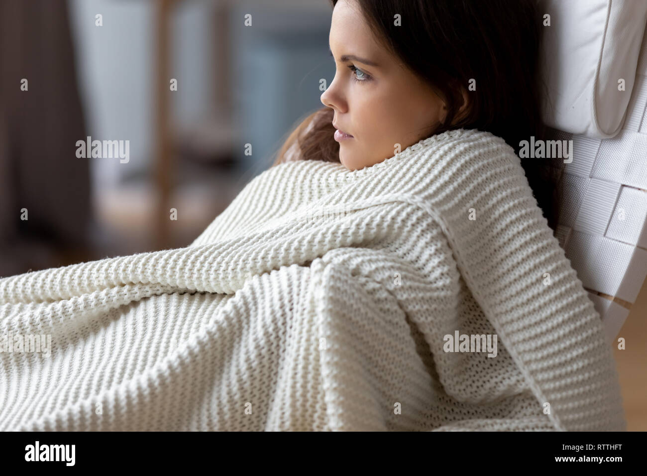 Attraente ragazza rilassante sotto coperta morbida in una sedia confortevole Foto Stock