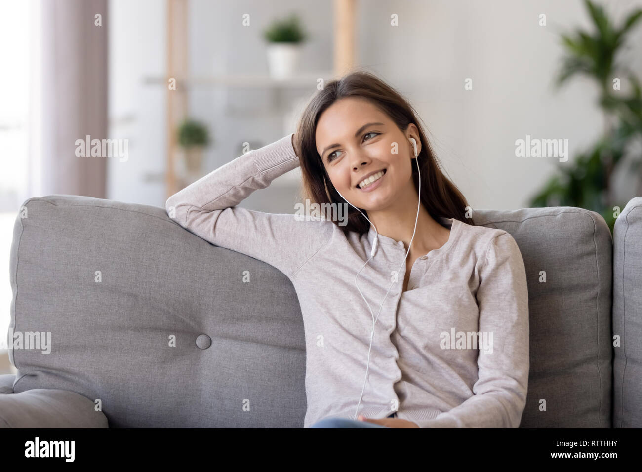 Sorridente giovane donna in auricolari, ascoltando la musica preferita Foto Stock