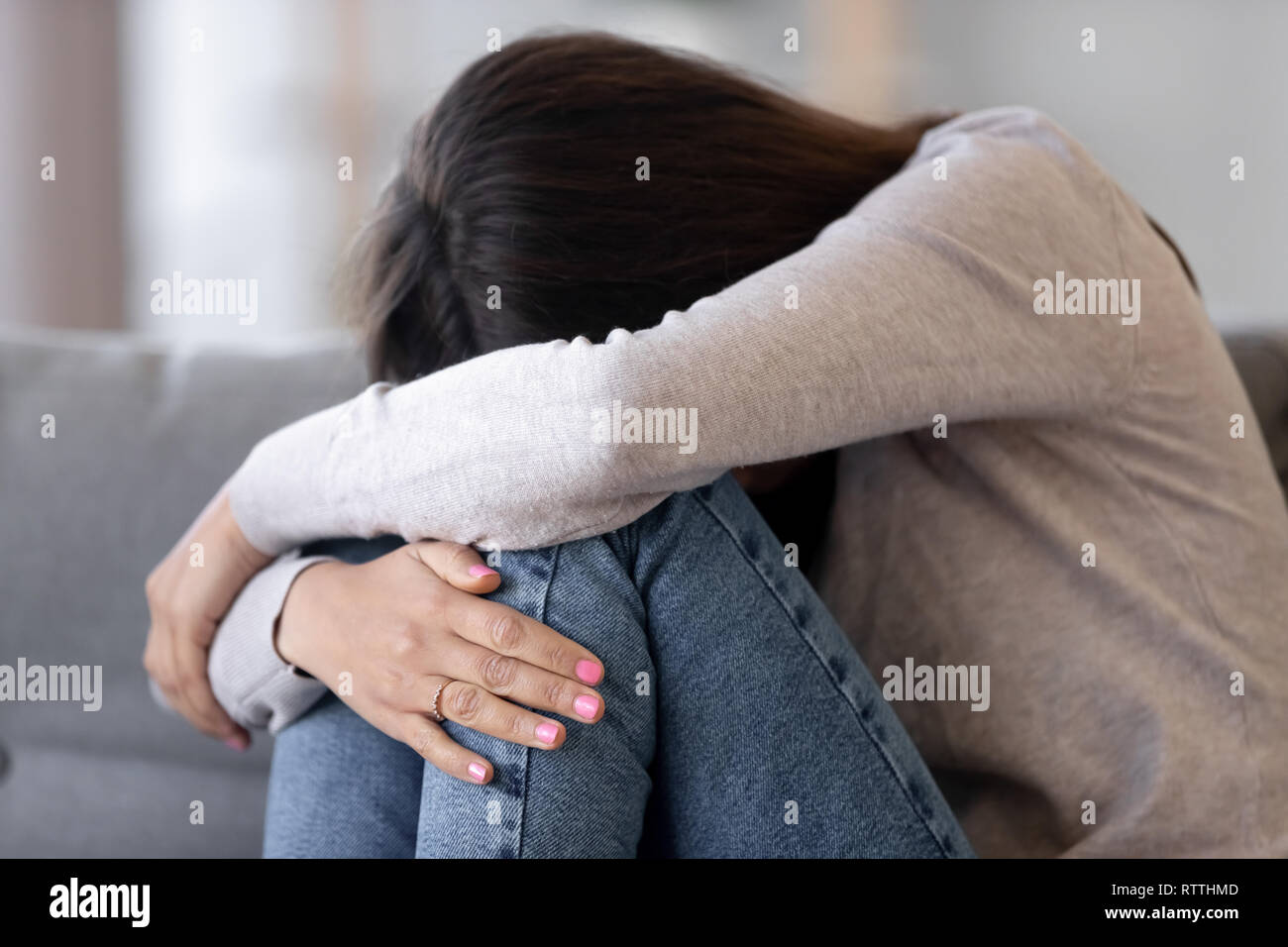 Sconvolto giovane donna abbracciando le ginocchia, piangere, sentirsi insoddisfatto Foto Stock