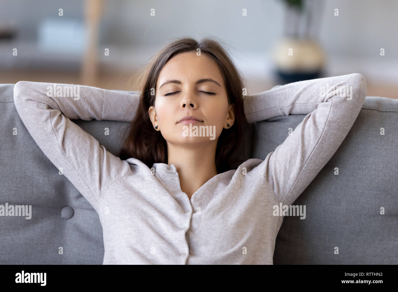 Tranquillo giovane donna con le mani dietro la testa in un momento di relax a casa Foto Stock