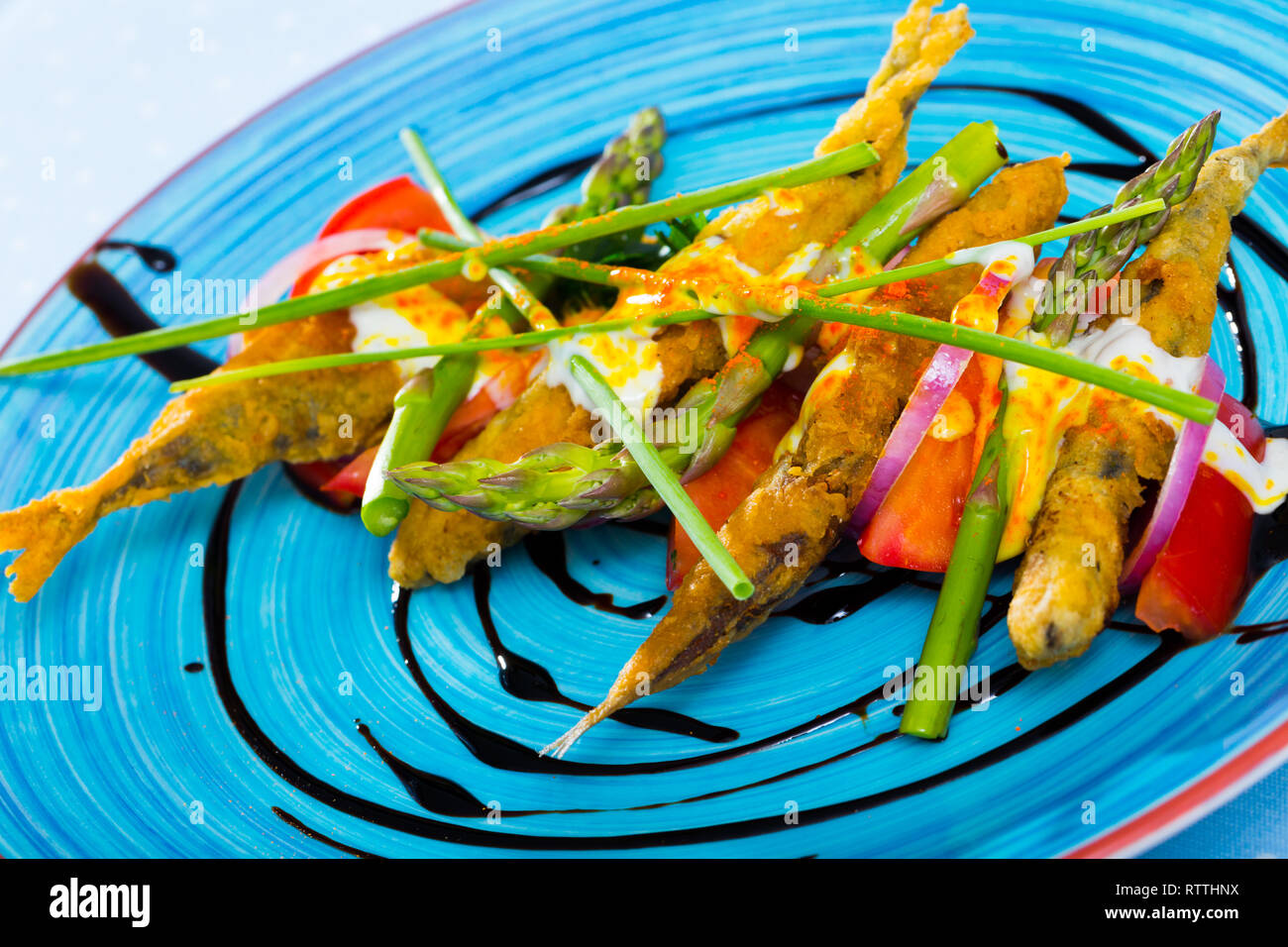 Sardine fritti in pastella con cremosa salsa di zenzero sul cuscino di pomodori dolci e pasta di aceto balsamico Foto Stock