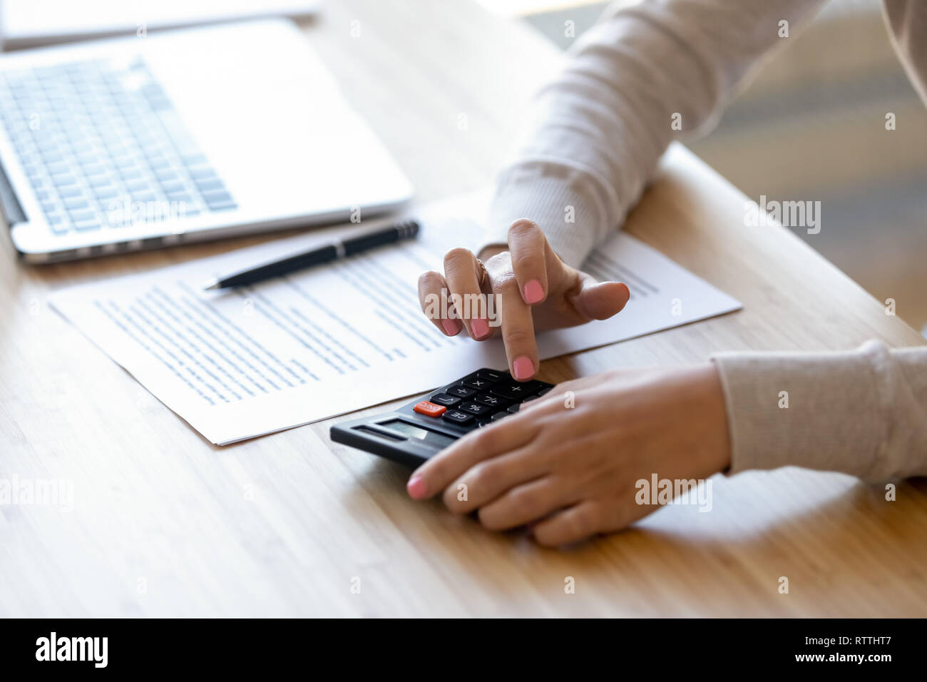 Vicino la giovane donna utilizzando la calcolatrice, calcolo finanziamento al luogo di lavoro Foto Stock