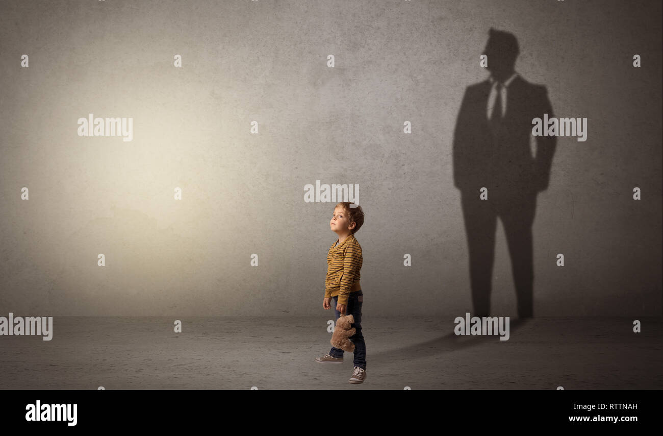 Little Boy immaginare che egli sarà uomo d affari e illustrando il suo futuro in una grande ombra Foto Stock